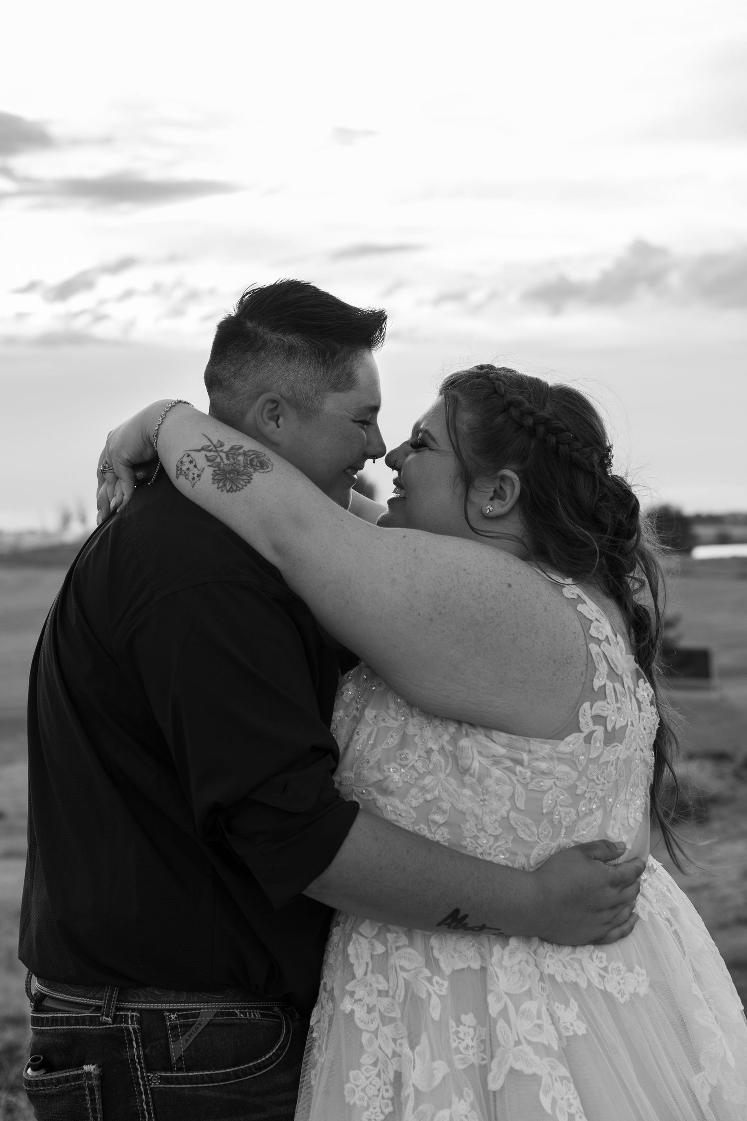 Black and white romantic wedding portraits showing tender embraces against a cloudy sky.