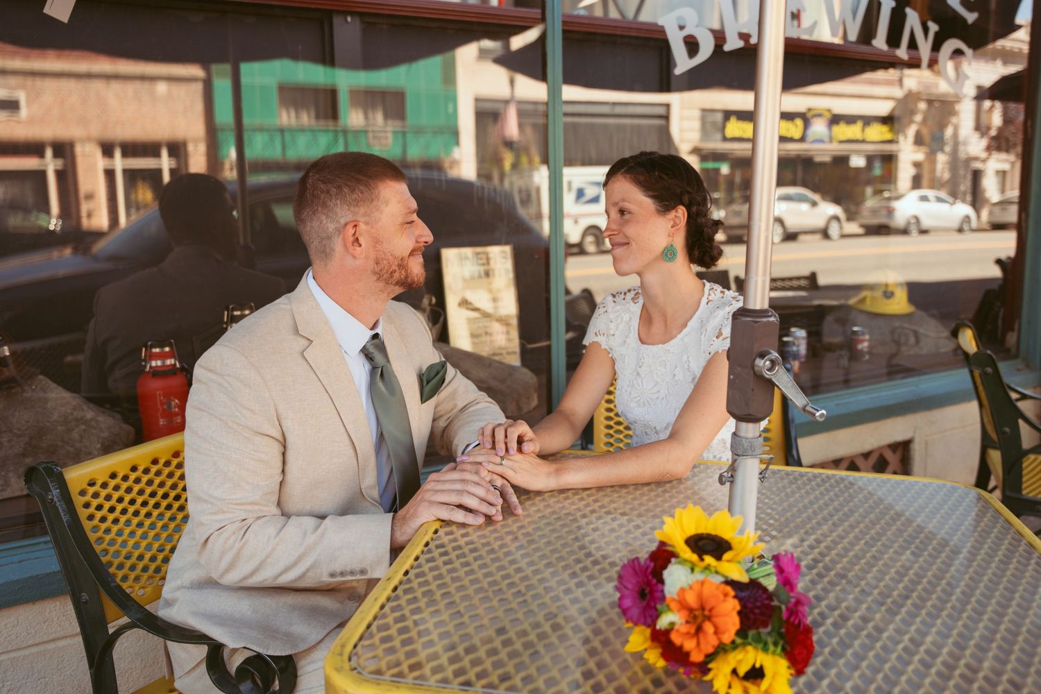 Couple sharing romantic moment at outdoor cafe table with colorful flower centerpiece.