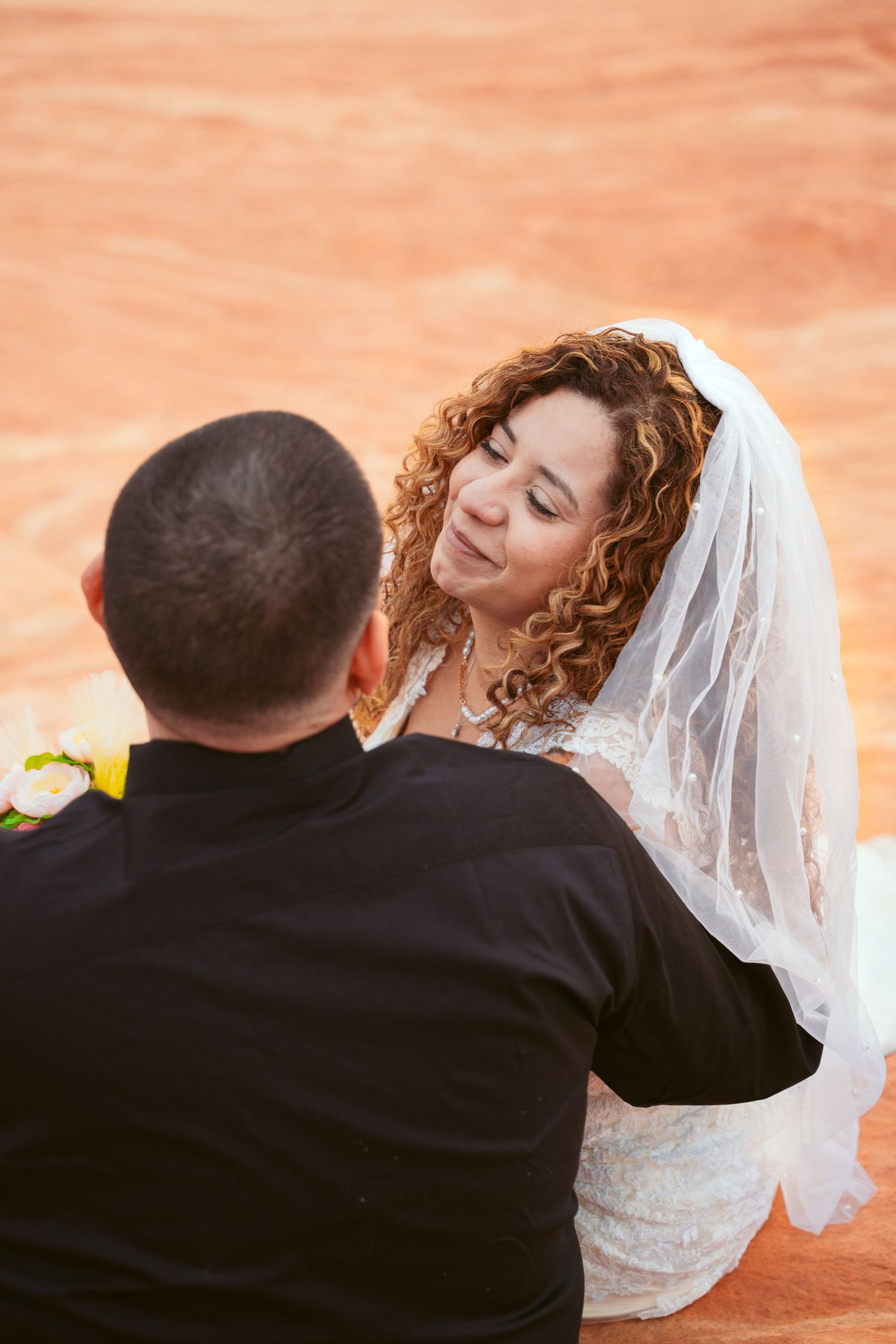 Intimate wedding photos taken against warm desert tones at sunset.