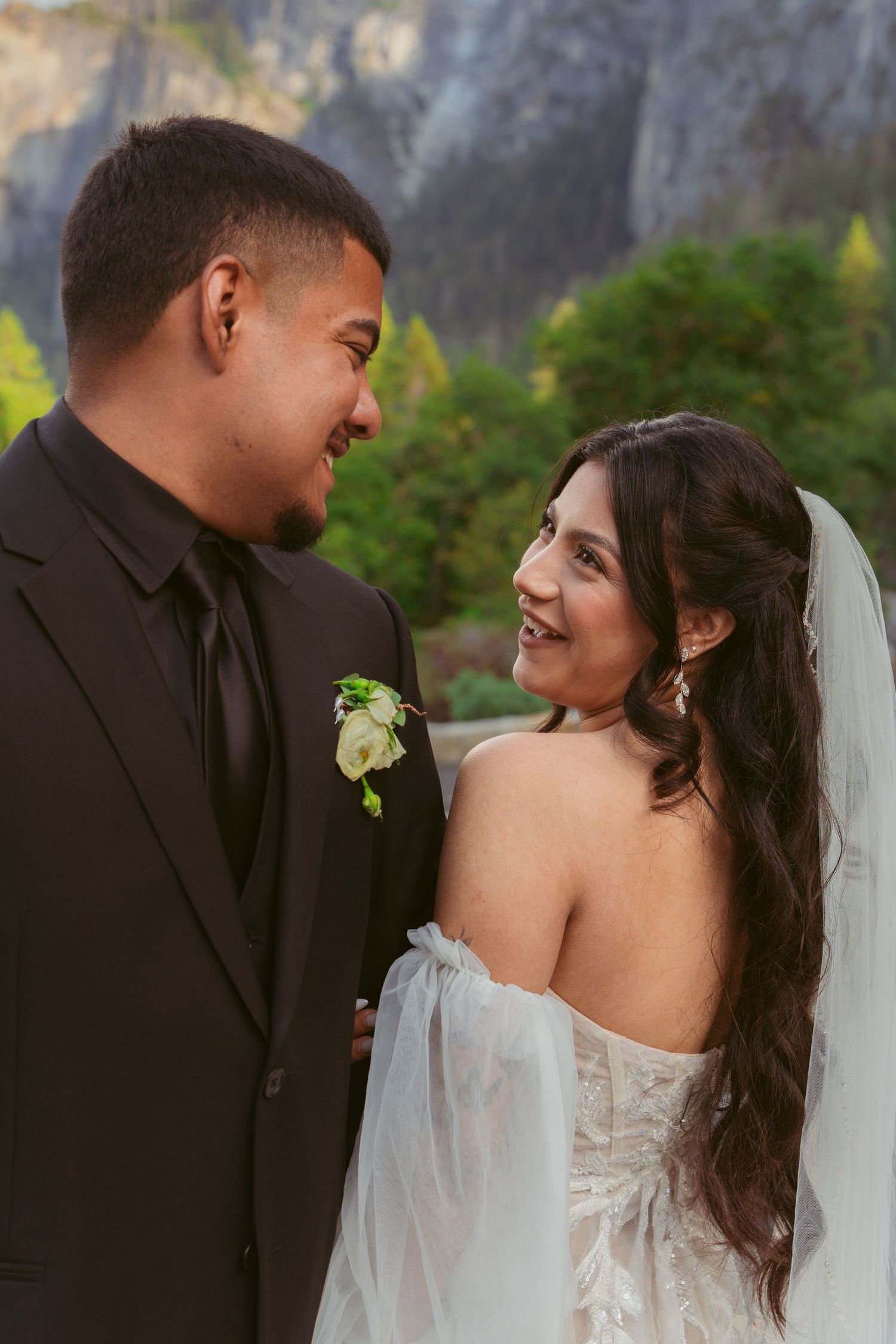 Wedding couple shares joyful moments against Yosemite's dramatic cliff backdrop.