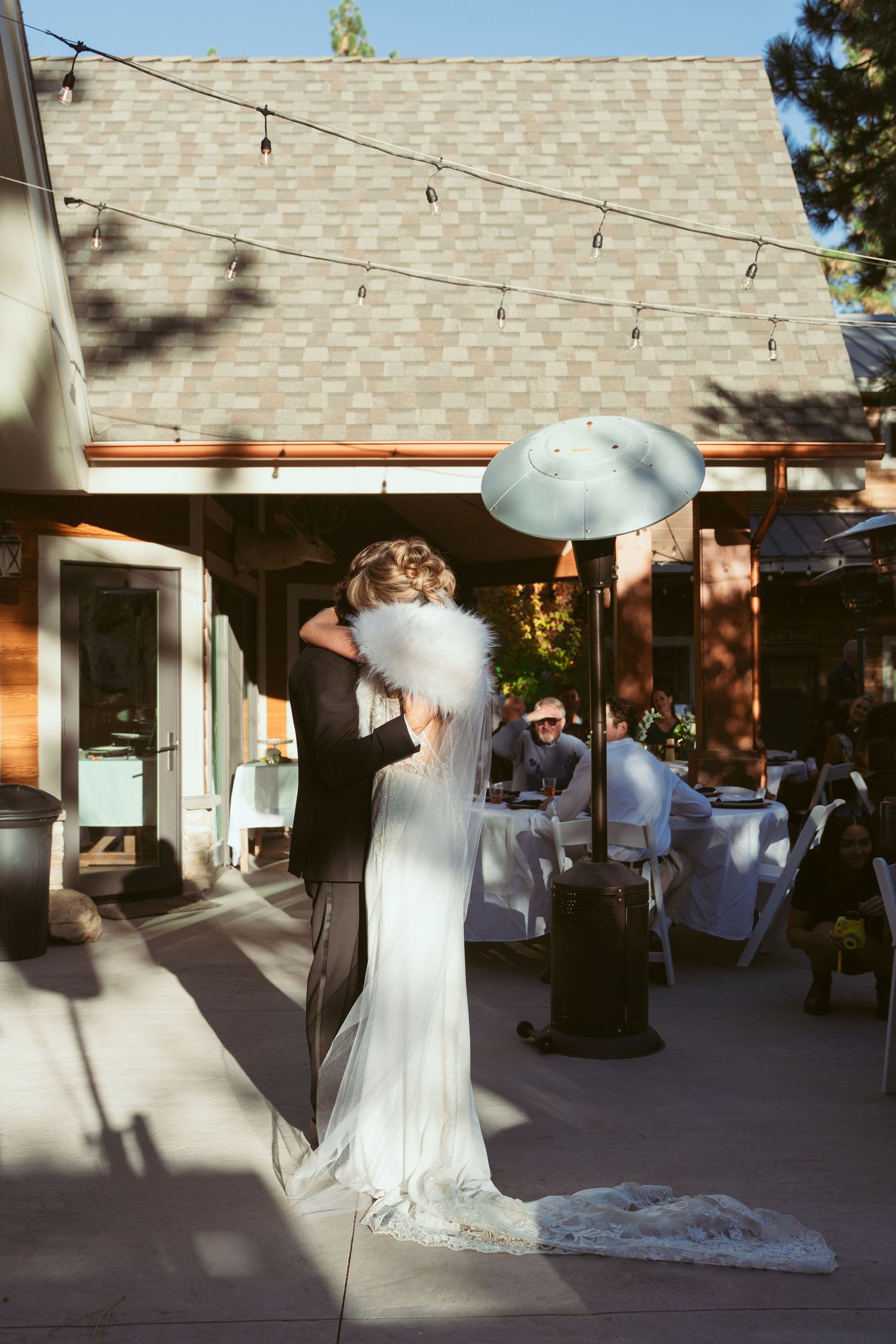 Sunlit outdoor wedding venue with string lights and white chairs set up for ceremony.