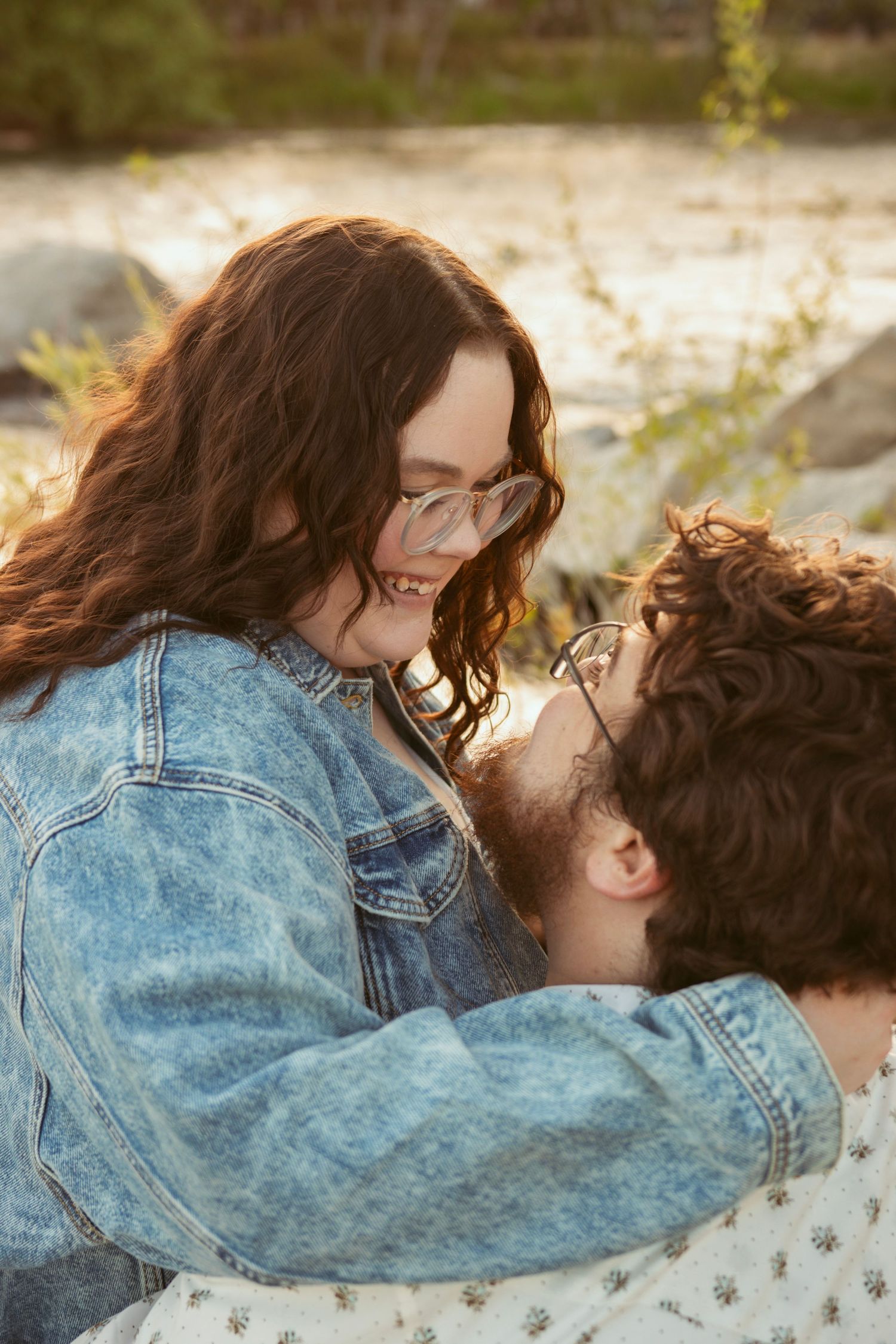 Intimate moment shared between two people near a waterfront at sunset.