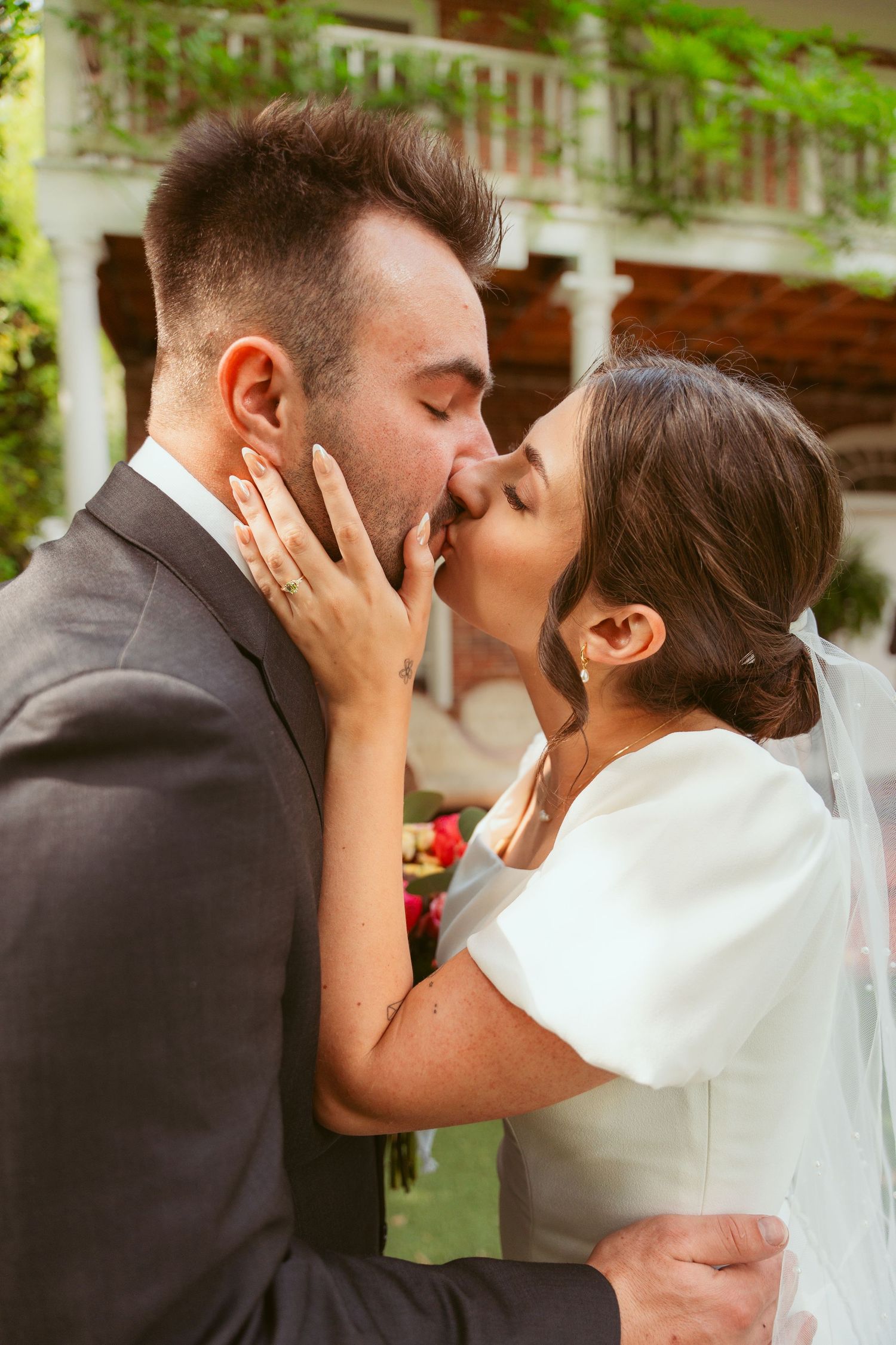 Romantic wedding couple shares an intimate kiss in a garden setting.