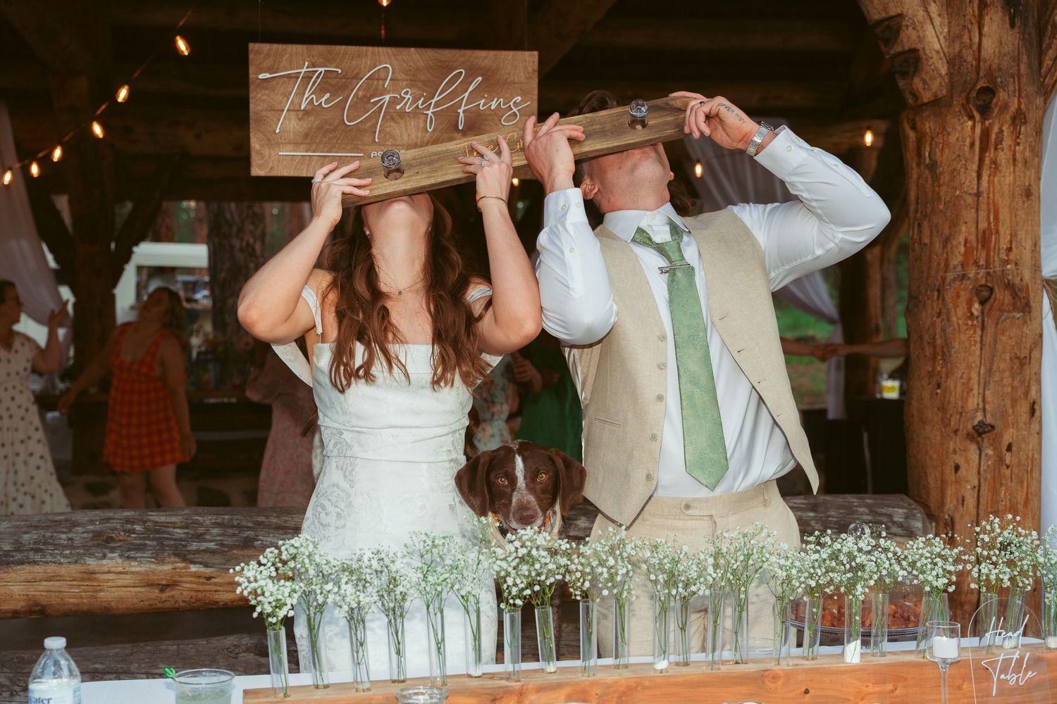 Couple taking celebratory shots at rustic wooden bar during wedding reception.