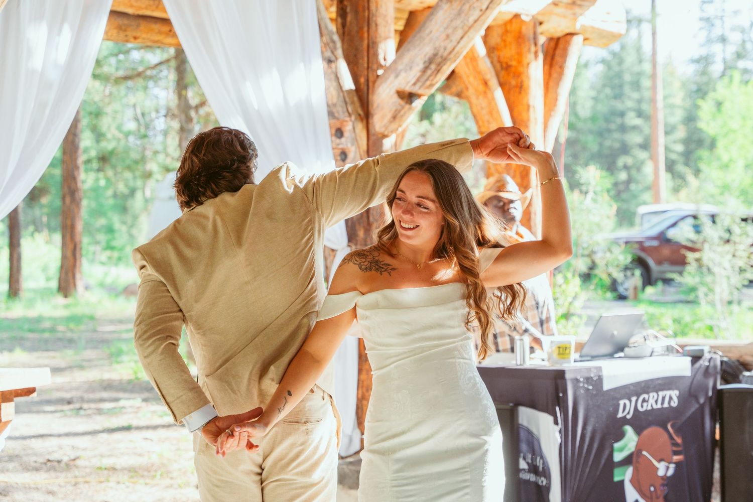 Couple dancing in an intimate moment under a wooden pavilion surrounded by pine trees.