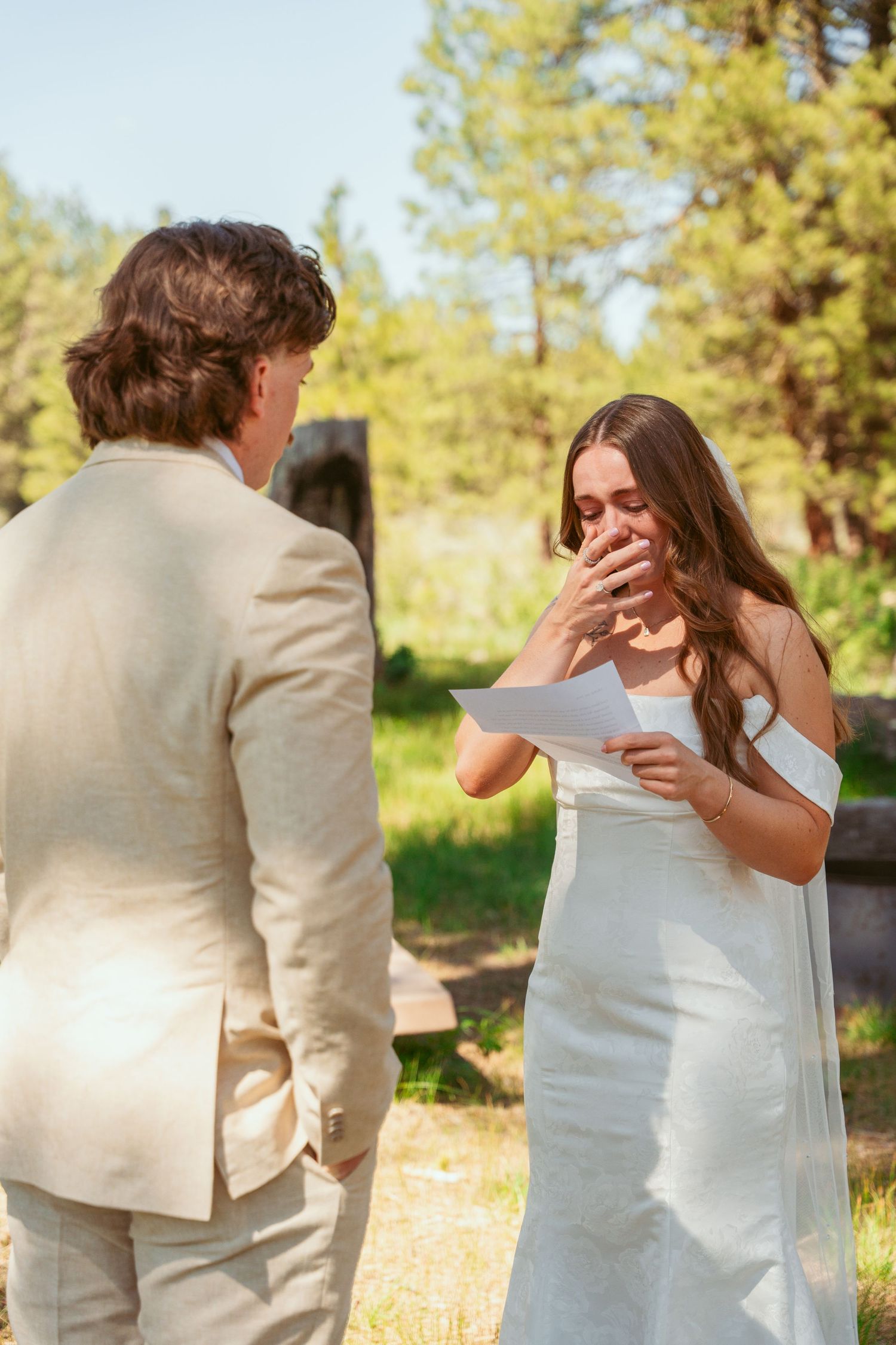 A bride and groom exchange heartfelt letters during their outdoor wedding ceremony.