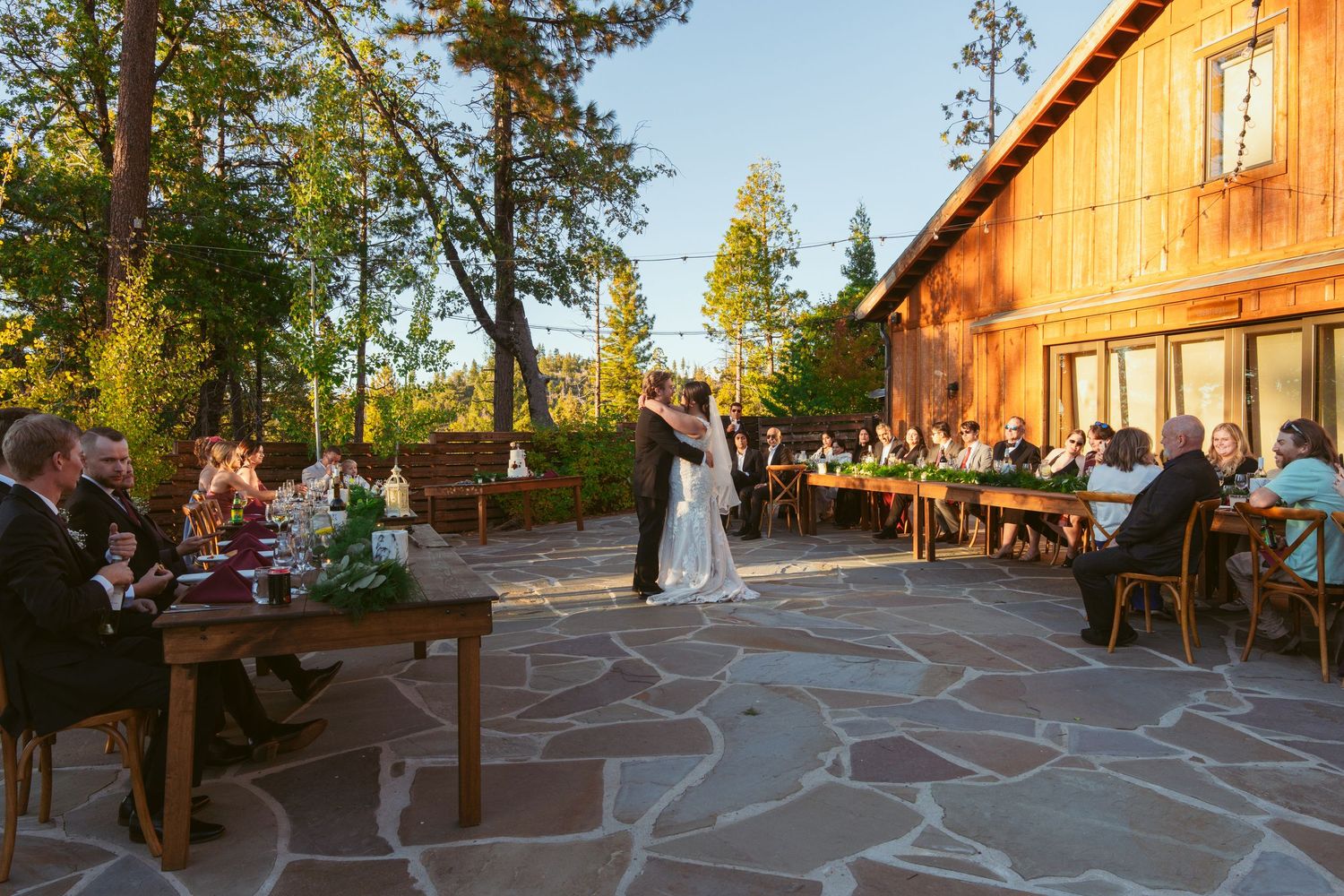 Rustic wooden lodge venue with stone patio and string lights at sunset.