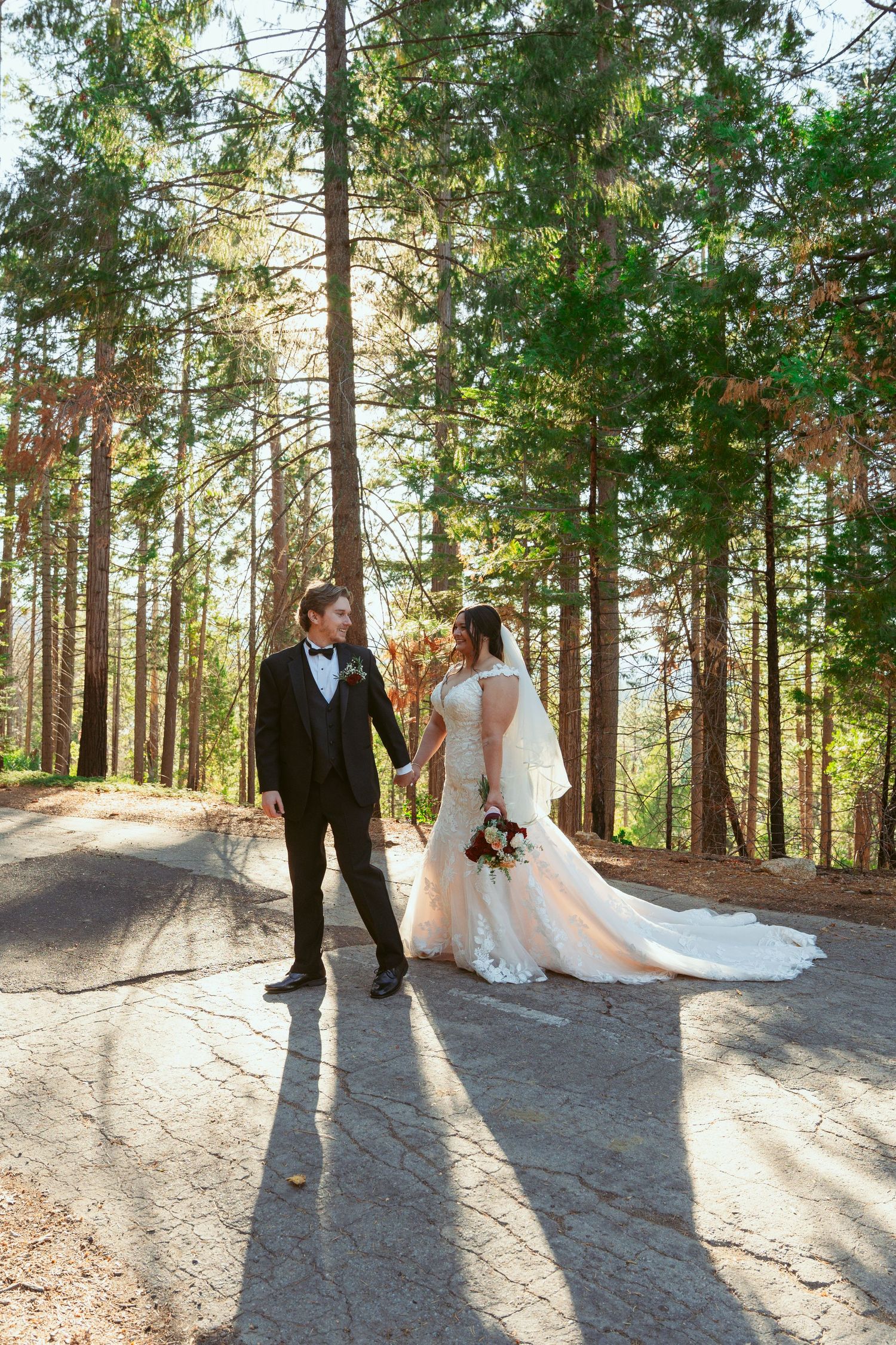 Wedding couple shares intimate moments along a scenic forest trail during golden hour.