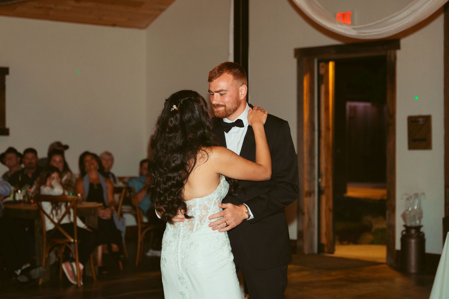 Wedding dance captured in a rustic venue with wooden ceiling beams and ambient lighting.