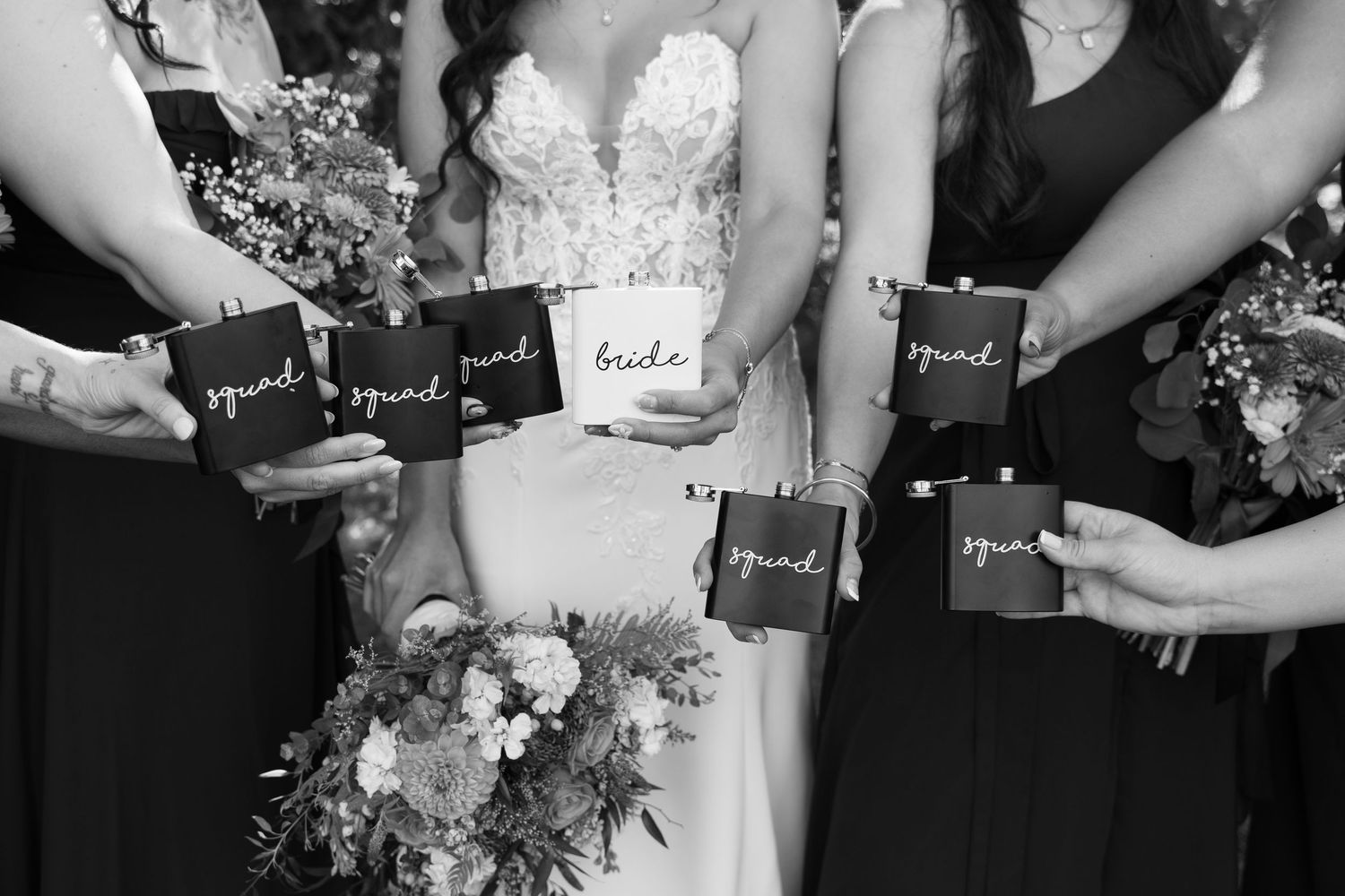 Black and white detail shot of wedding party holding personalized cards with bouquets.