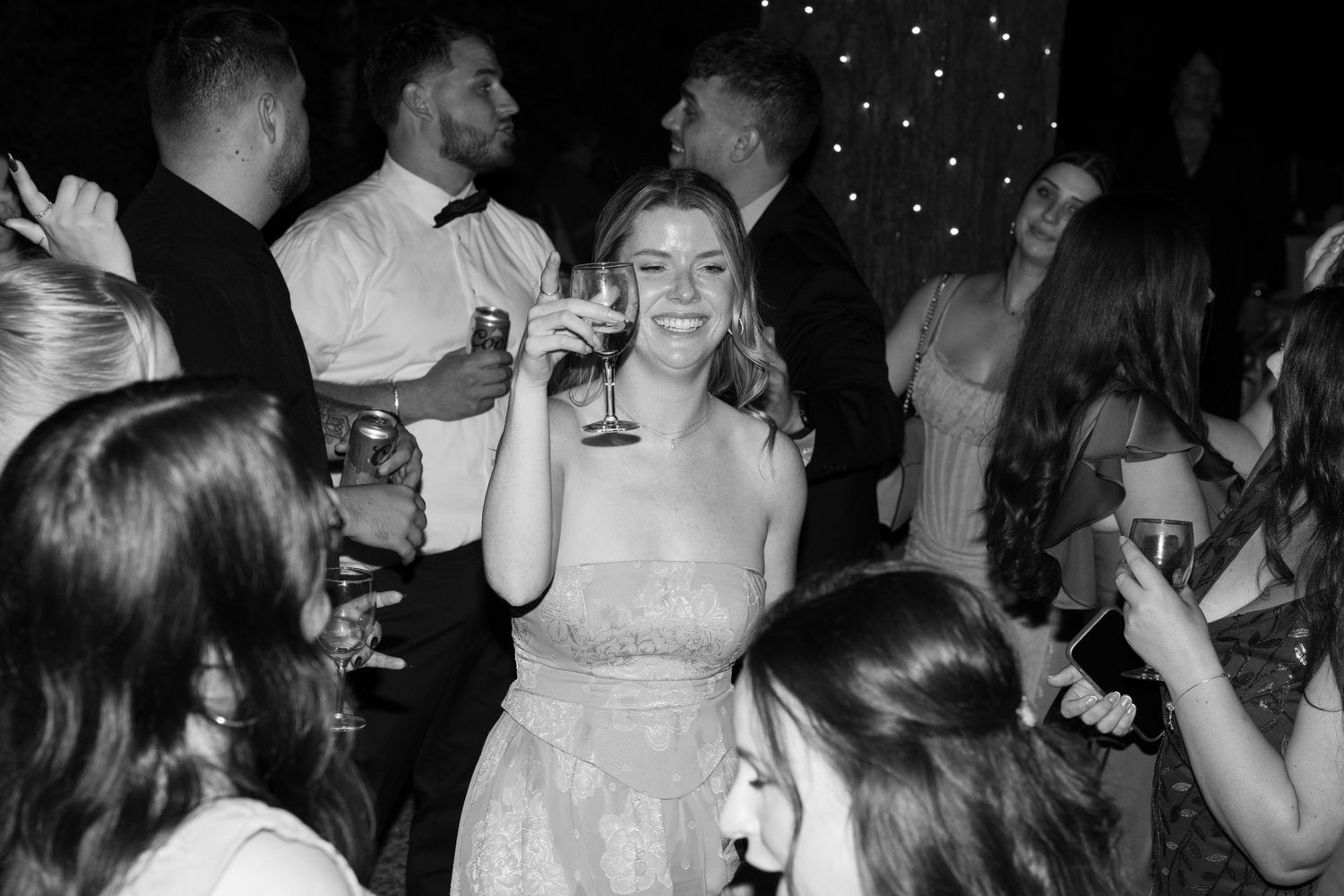Wedding reception dance party with guests celebrating under twinkling lights.