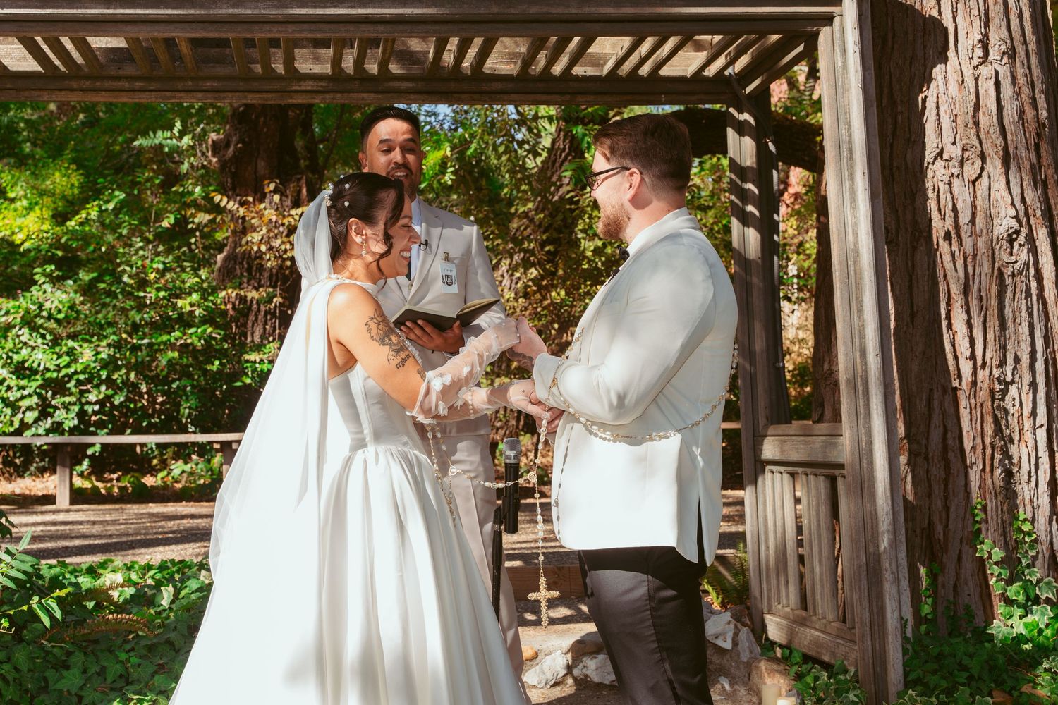 A wedding ceremony exchange taking place in a rustic wooden gazebo setting.