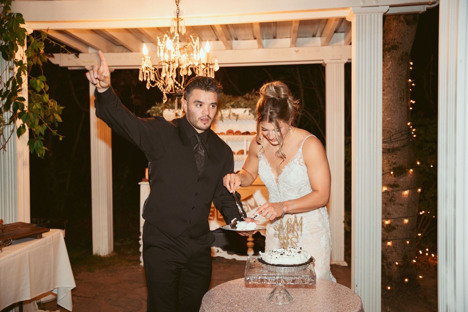 A celebratory moment during a wedding reception as a couple cuts their cake under twinkling lights.