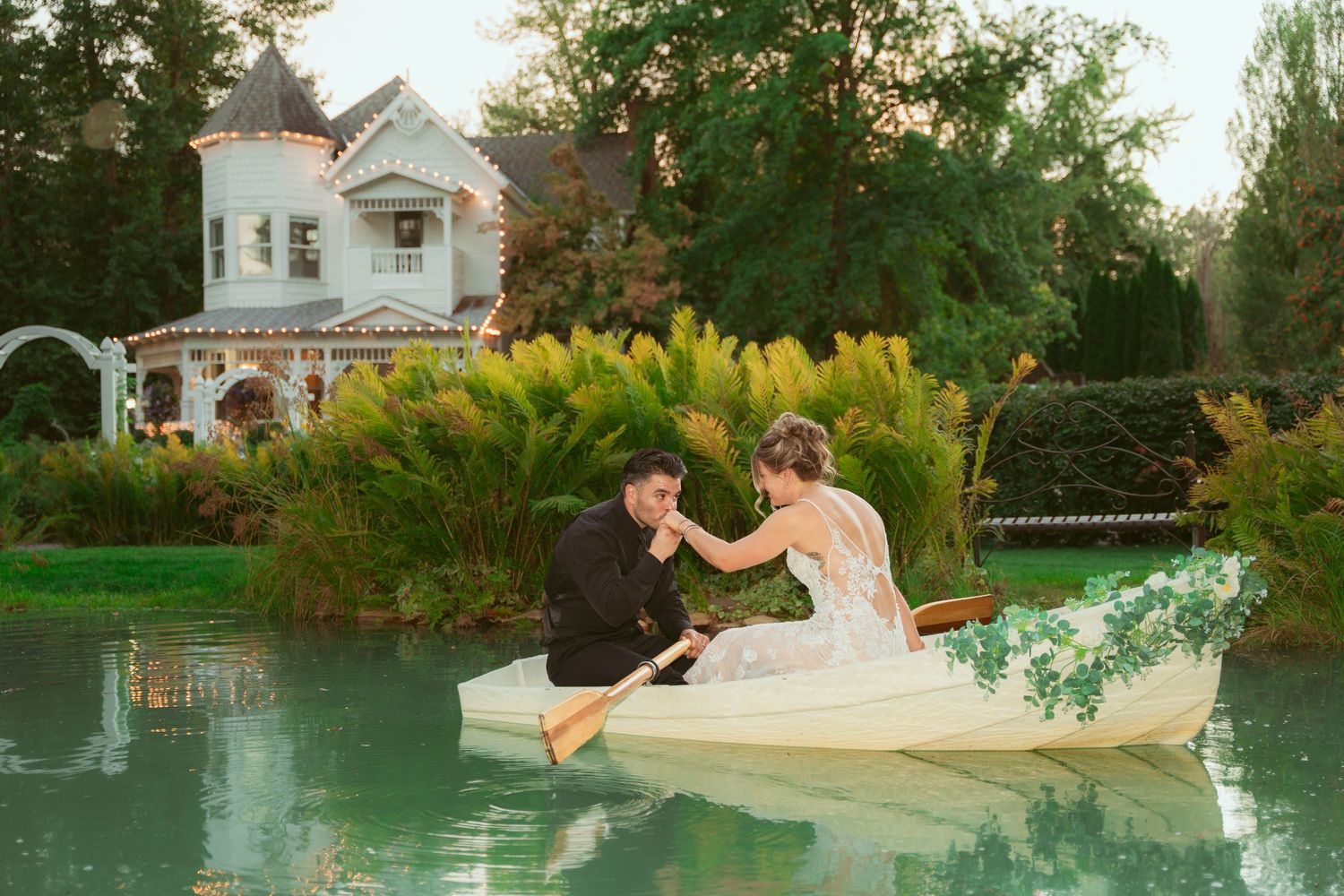 Creative wedding portrait session by a pool with white house visible in background.