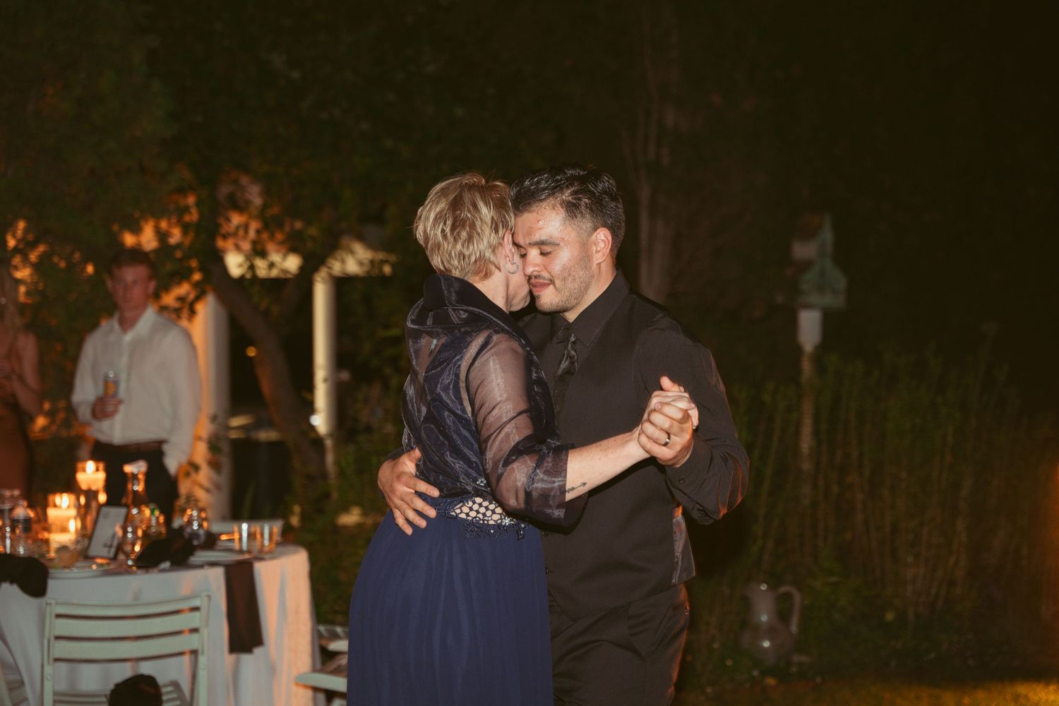 Couples slow dancing at a romantic outdoor evening wedding reception.