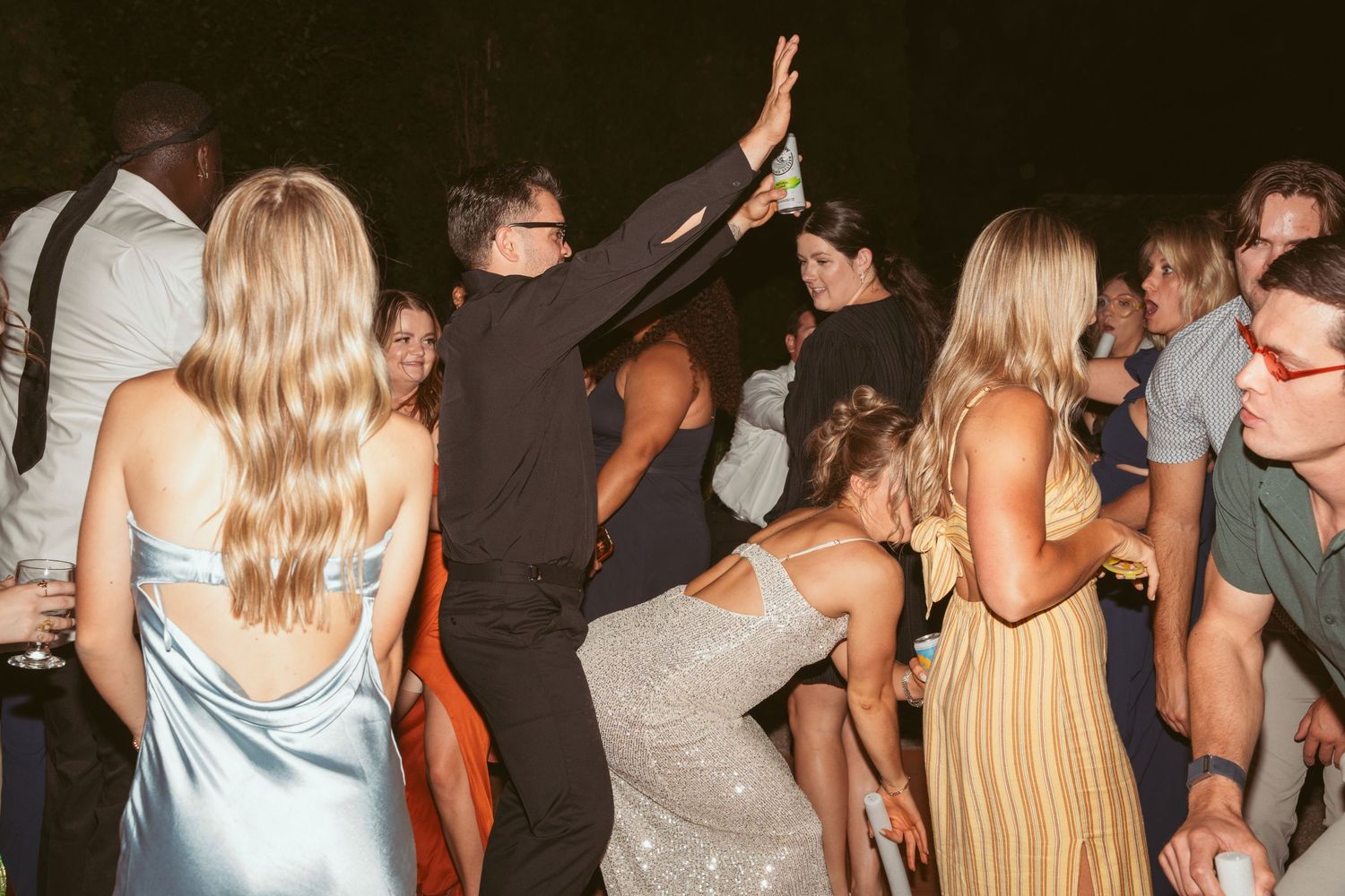 Wedding guests dancing and celebrating together at an evening reception party.
