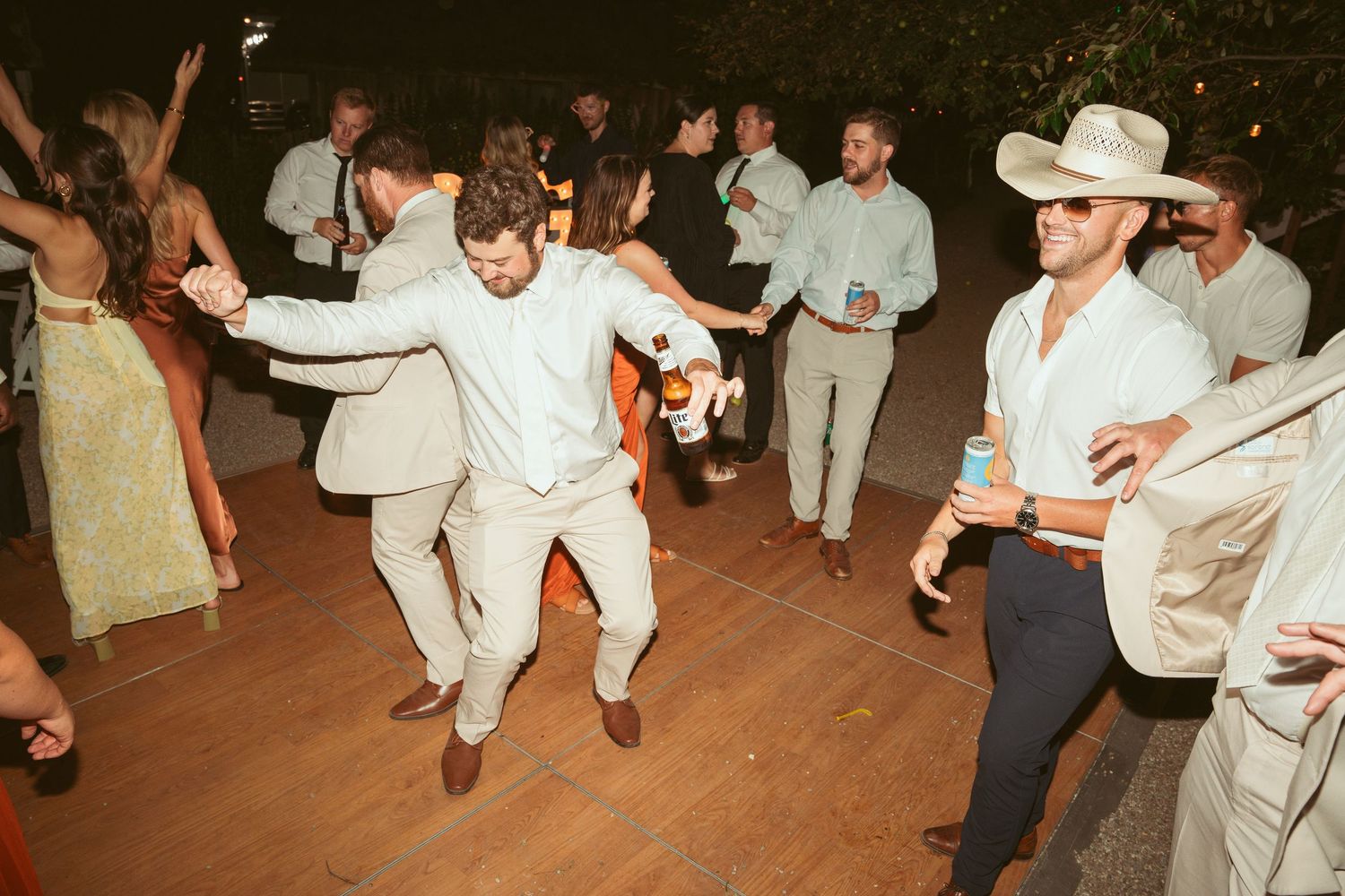 Guests showing off dance moves on outdoor dance floor at evening wedding celebration.