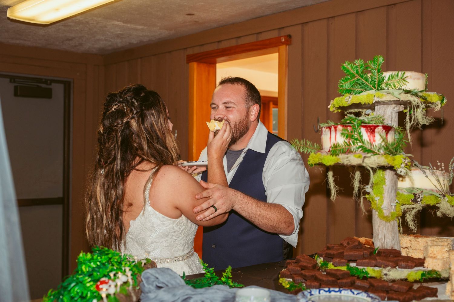 A joyful cake-feeding moment between newlyweds at their wedding reception.