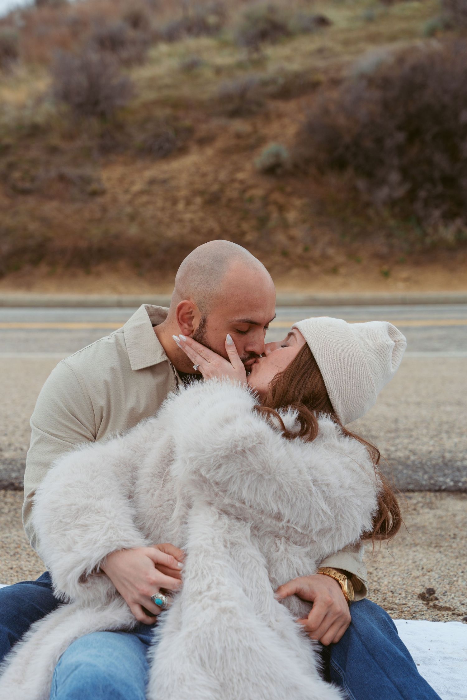A couple shares an intimate moment while sitting together outdoors.