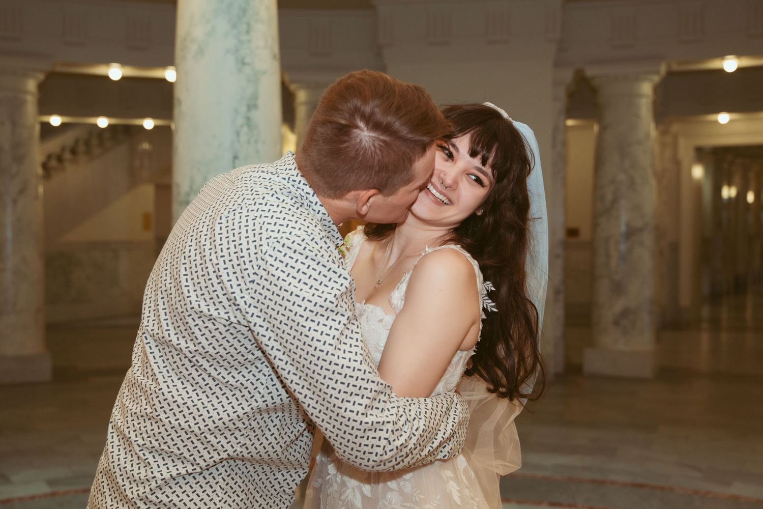 Wedding couple sharing romantic moments in an elegant indoor venue with columns.