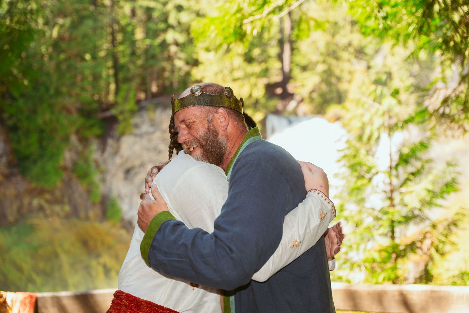 A couple shares tender moments in a wooded outdoor setting wearing renaissance-style wedding attire.