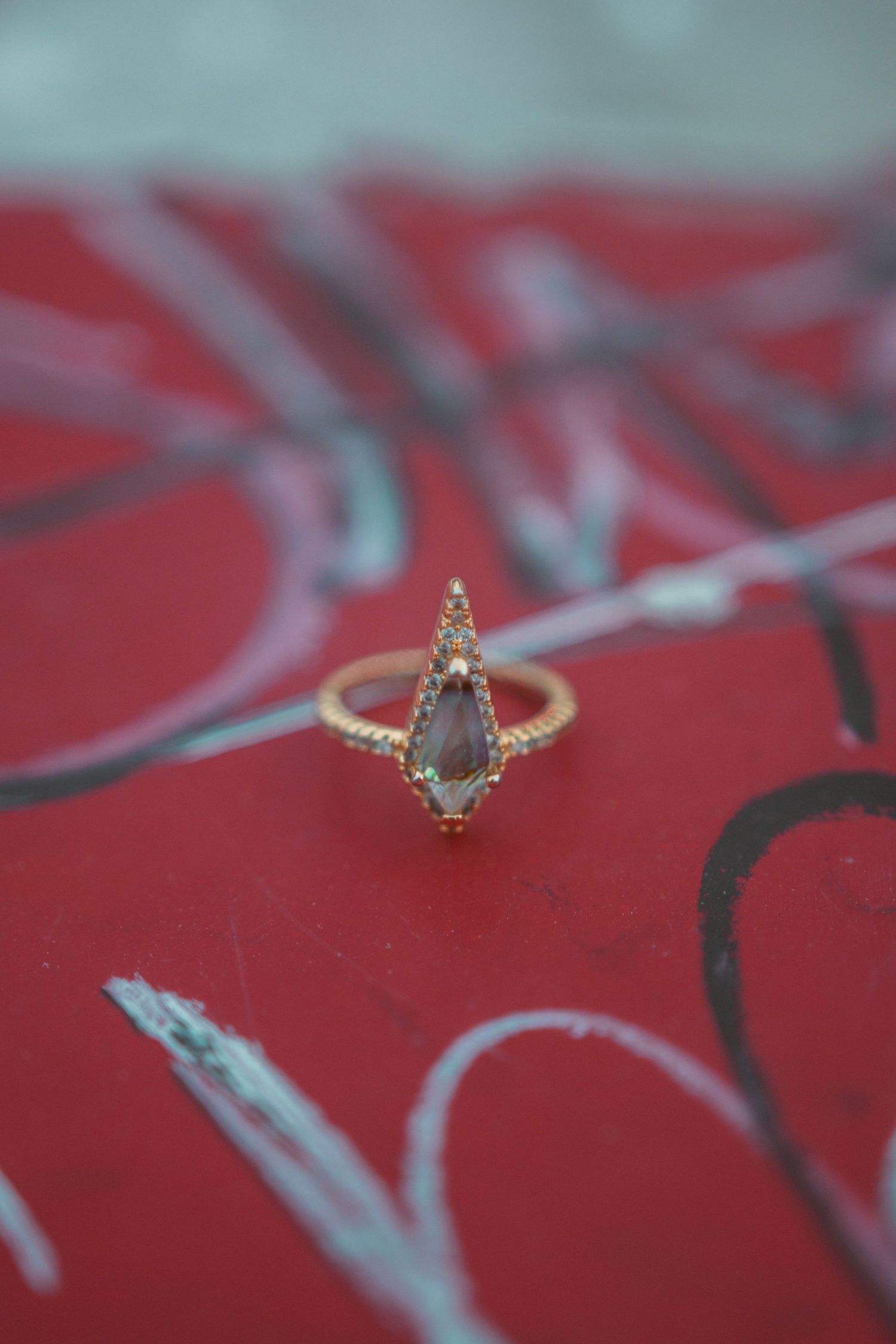 Close-up of a delicate gold ring with intricate details on red background.