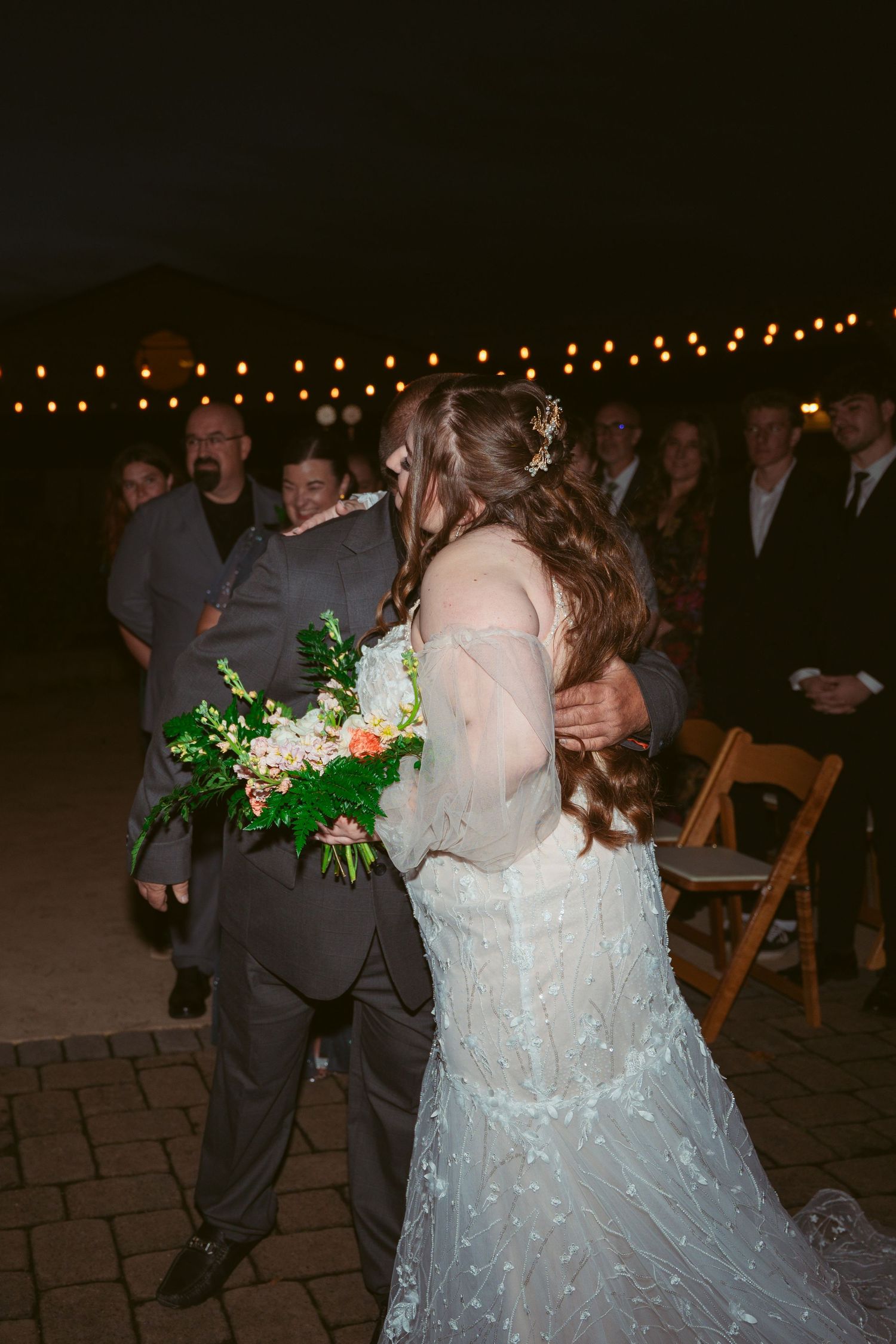 Wedding celebration with dancing couples in formal attire under string lights.