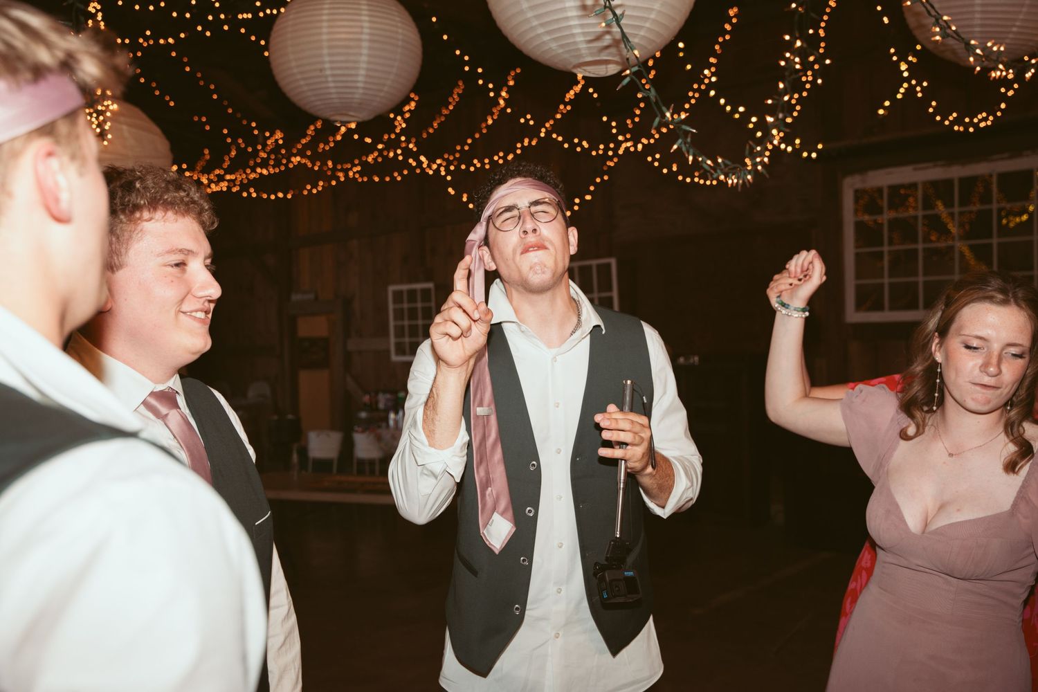 Wedding guests enjoying themselves on the dance floor under ambient string lighting.