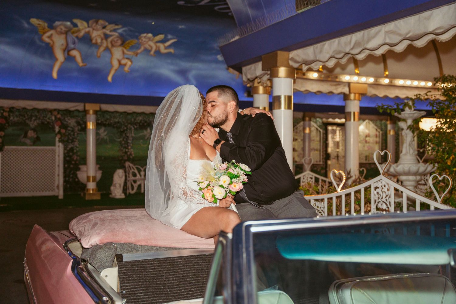 Newlyweds pose for romantic photos by an illuminated swimming pool during evening celebrations.