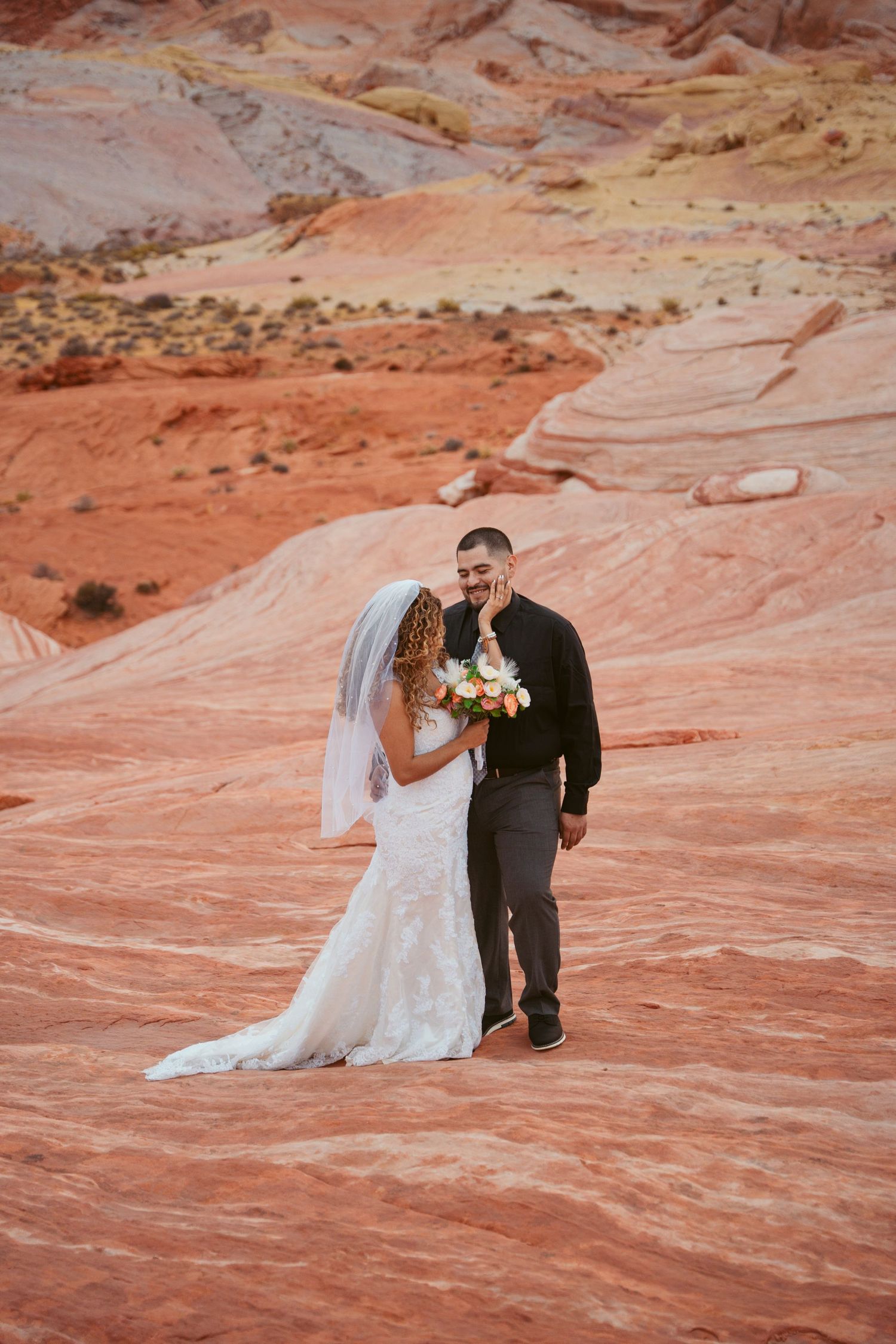 Wedding photography session on striking red rock formations in desert landscape.