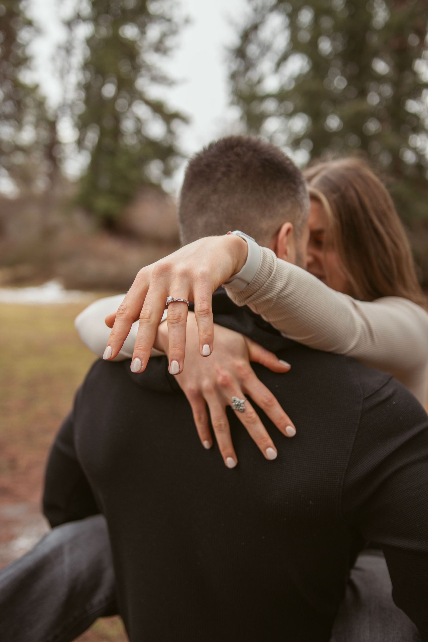 Close-up shot showing hands with engagement ring against dark clothing.