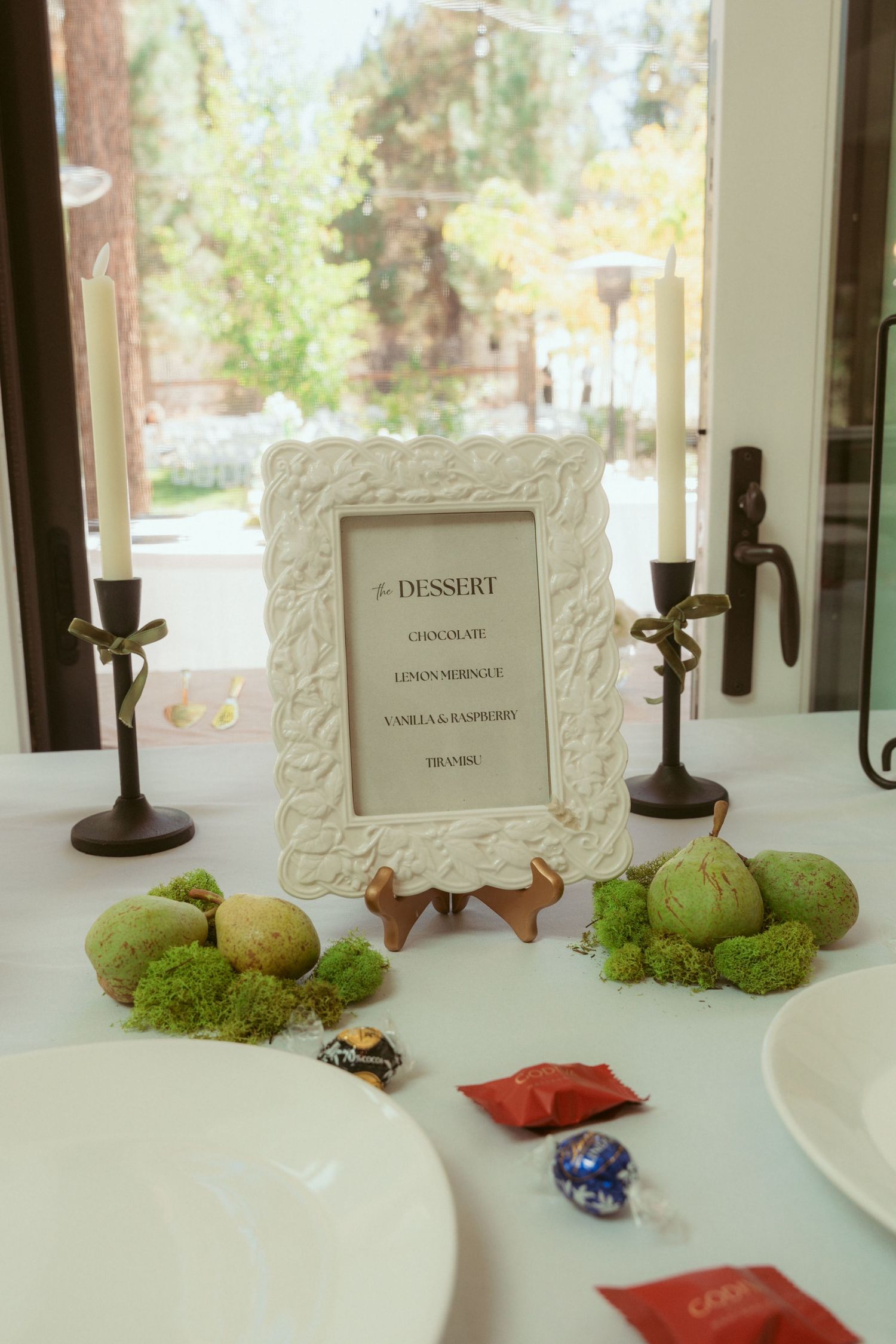 Vintage-style framed table numbers with candles and moss decorations.