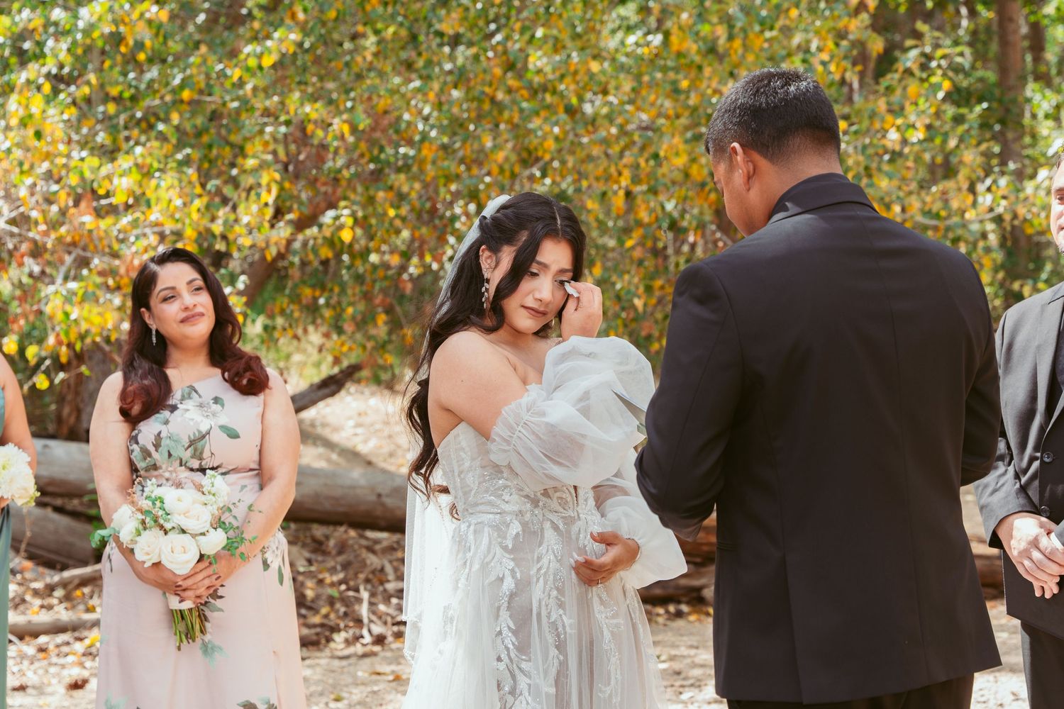 Wedding party celebrates outdoors with joyful dancing and embraces in an autumn setting.