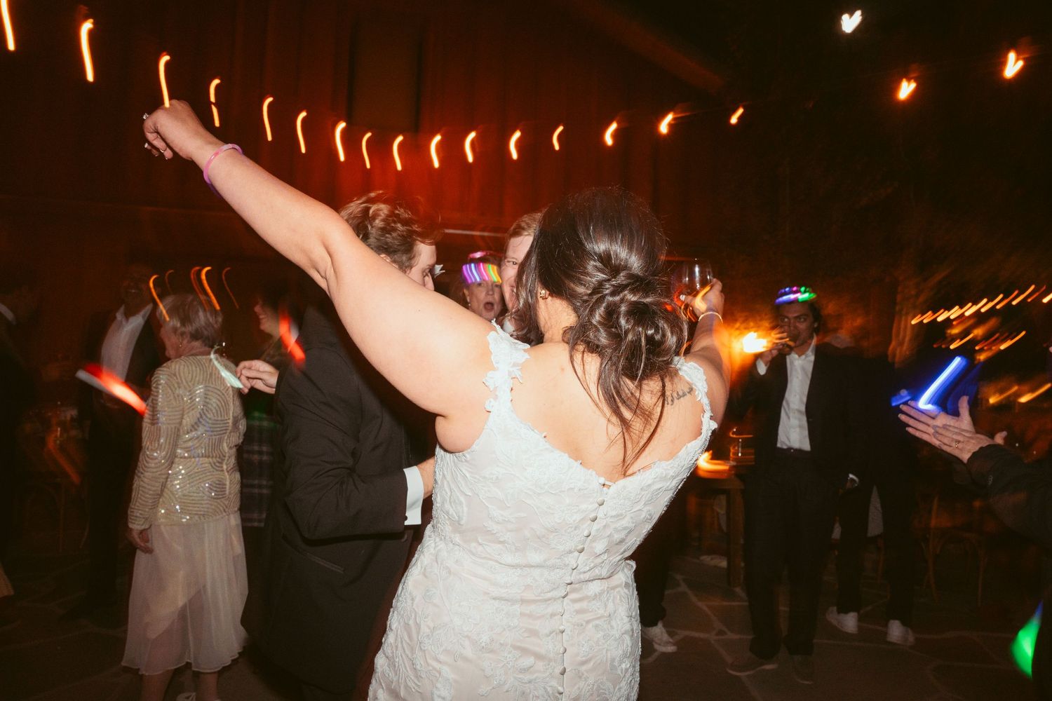 Wedding reception dance party with string lights and guests enjoying the celebration.