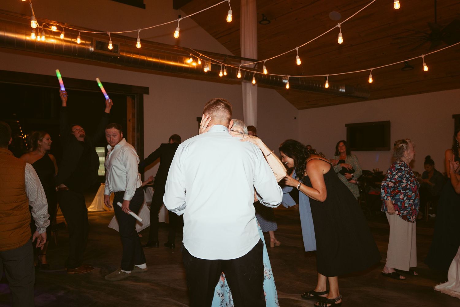 Guests enjoying themselves on a dance floor beneath decorative string lighting.