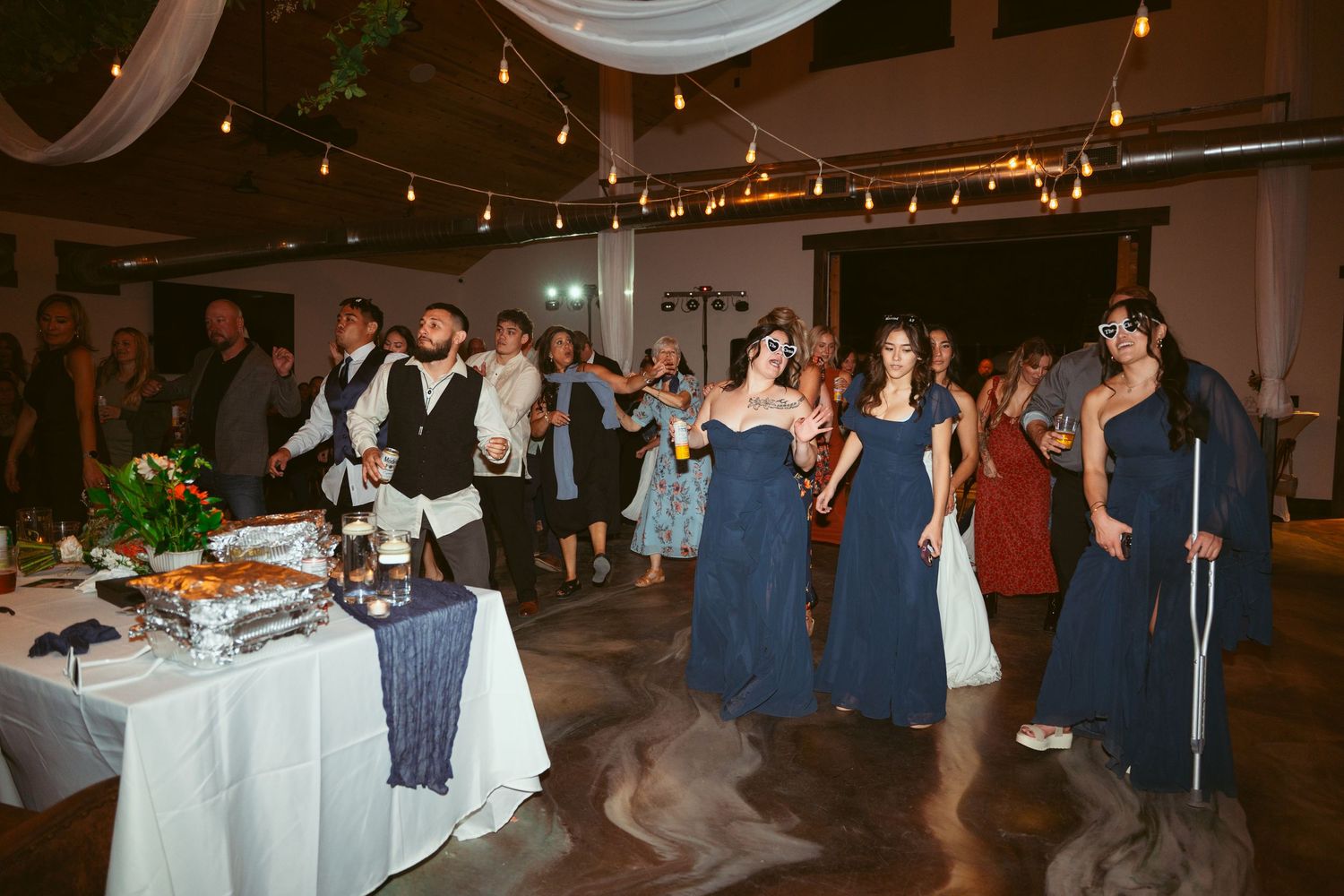 Large group of wedding guests enjoying reception party on dance floor.