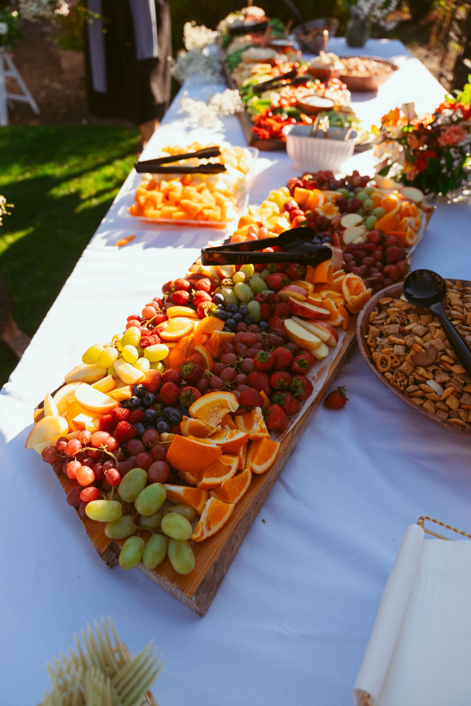Elegant charcuterie board with fresh fruits, cheeses and meats displayed on white tablecloth.