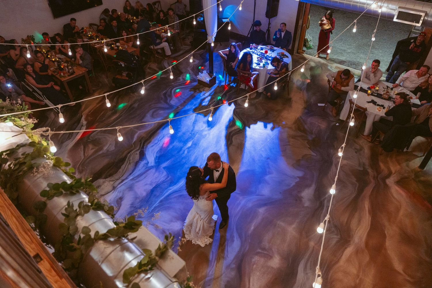 Wedding dance floor illuminated with blue lighting and string lights from above.