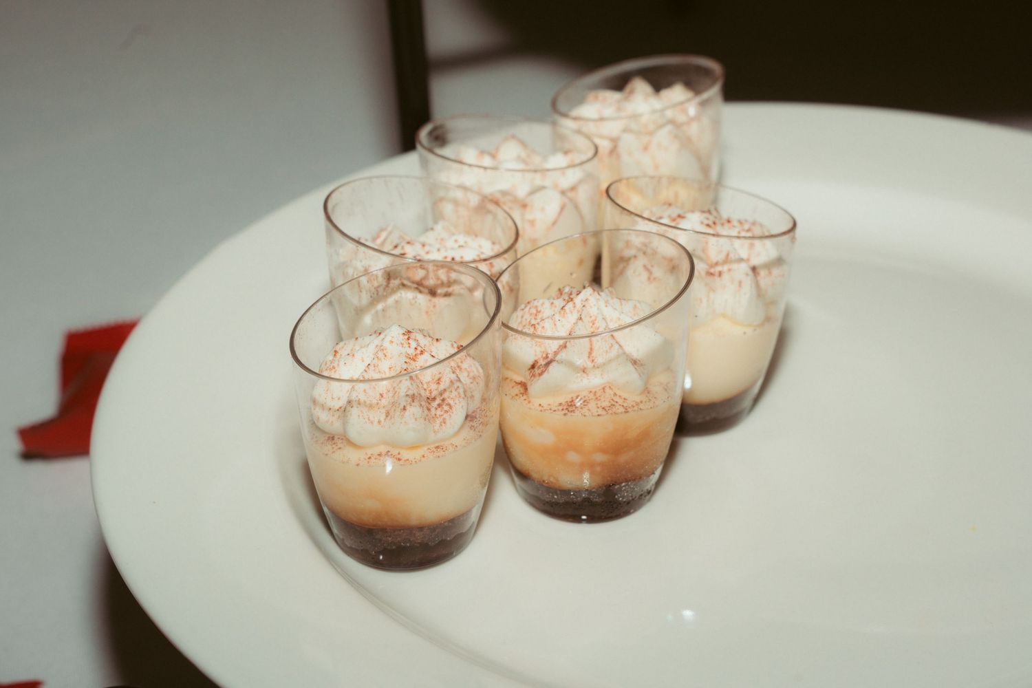 Small glass dessert cups filled with creamy mousse arranged on a white serving platter.