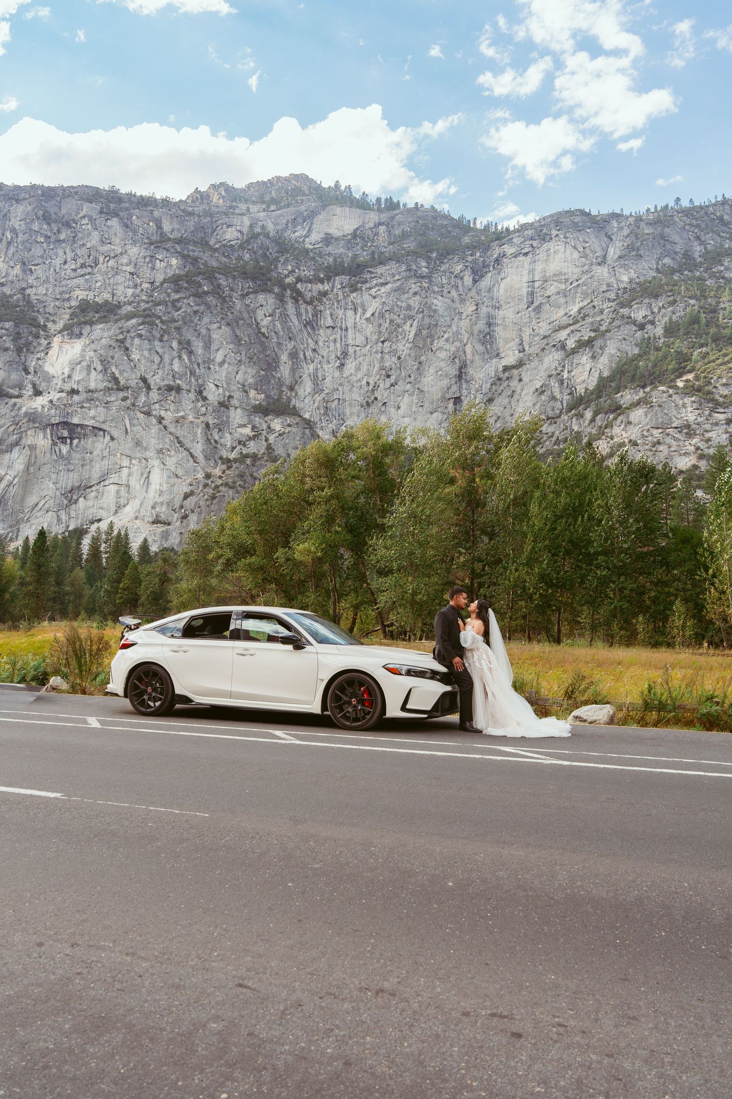 White limousine parked on road with dramatic Yosemite cliffs and mountains in background.