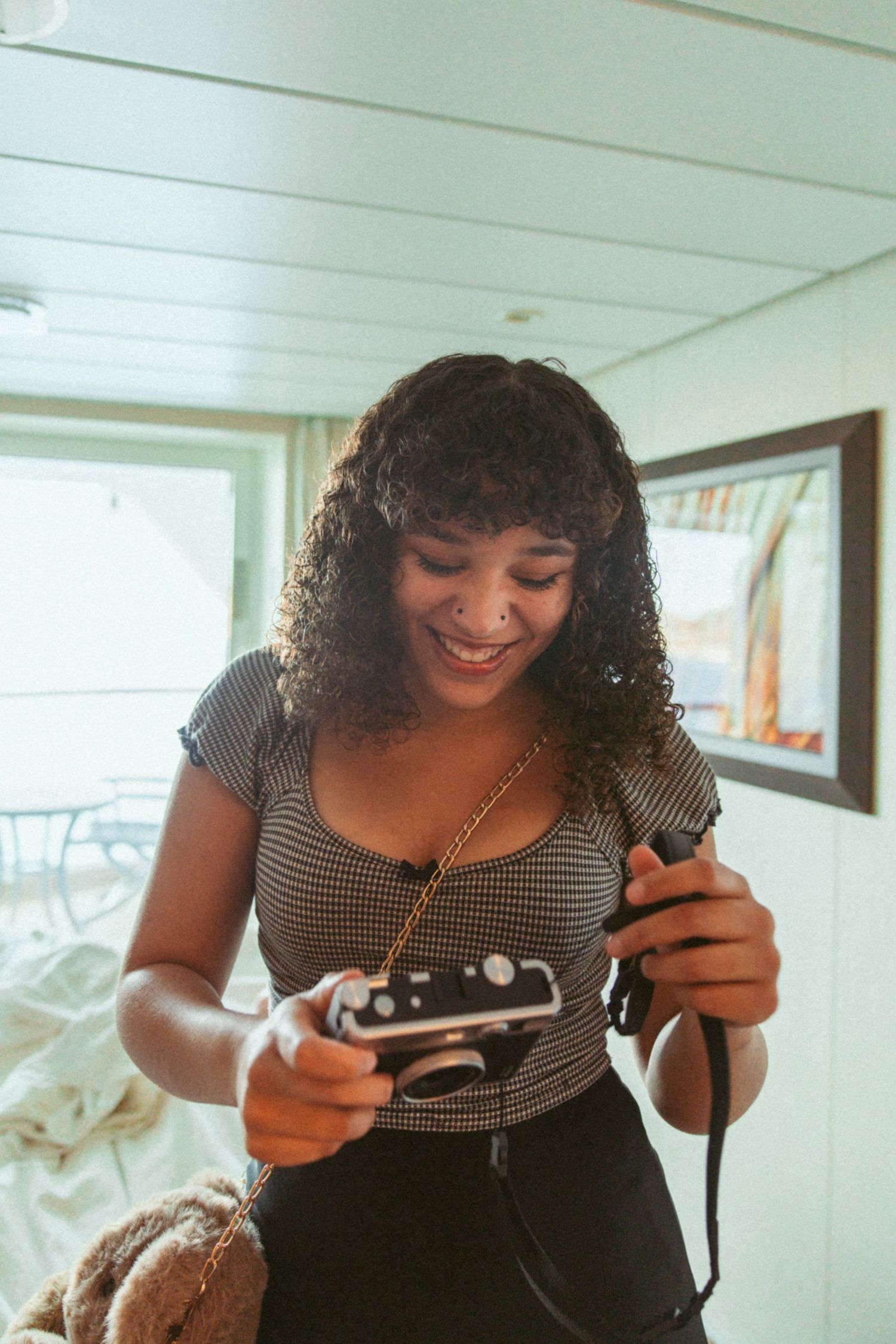 Person with curly hair examines something closely in an indoor setting.