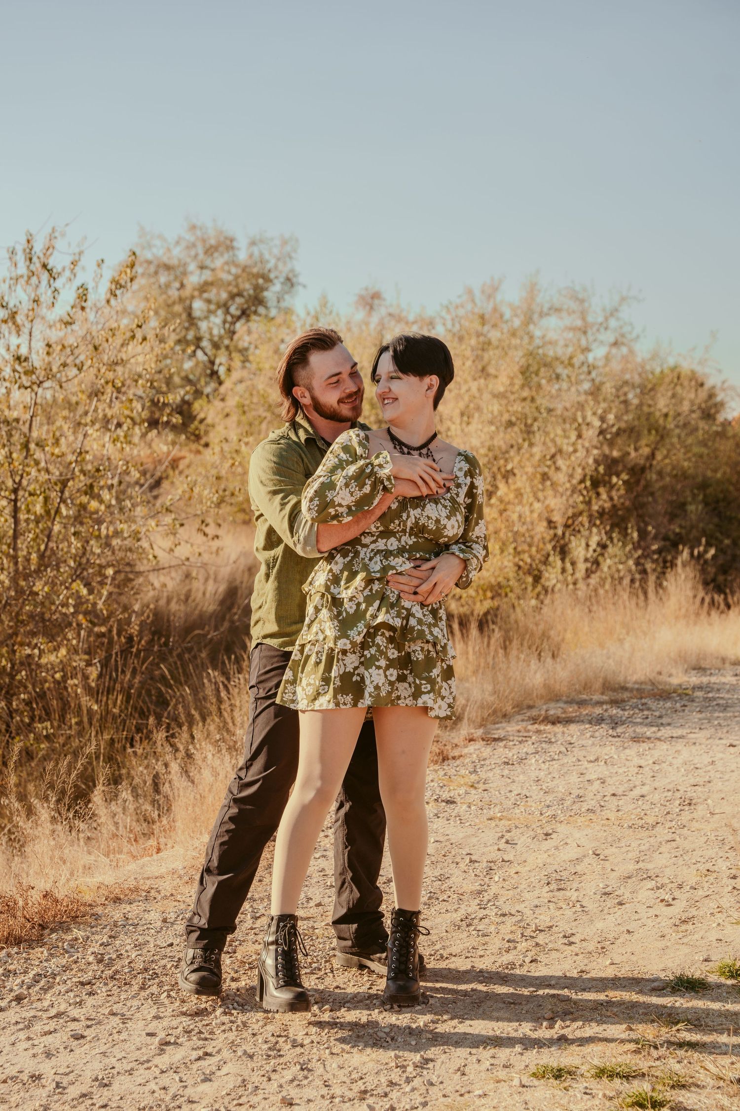 A couple shares an intimate dance moment on a desert trail during golden hour.