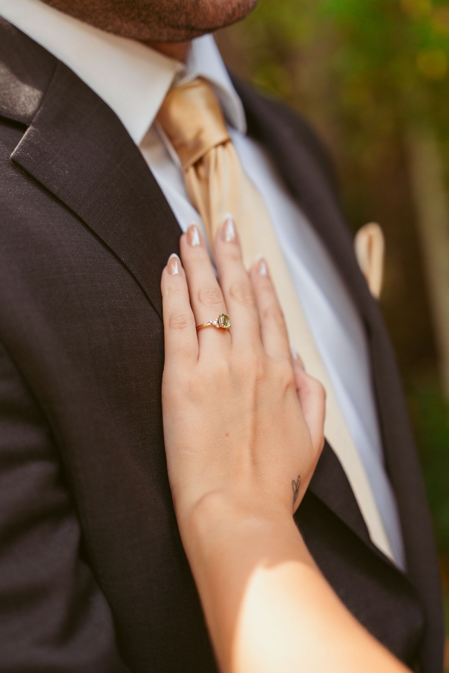 Close up of hands with wedding ring against formal black suit and tie.
