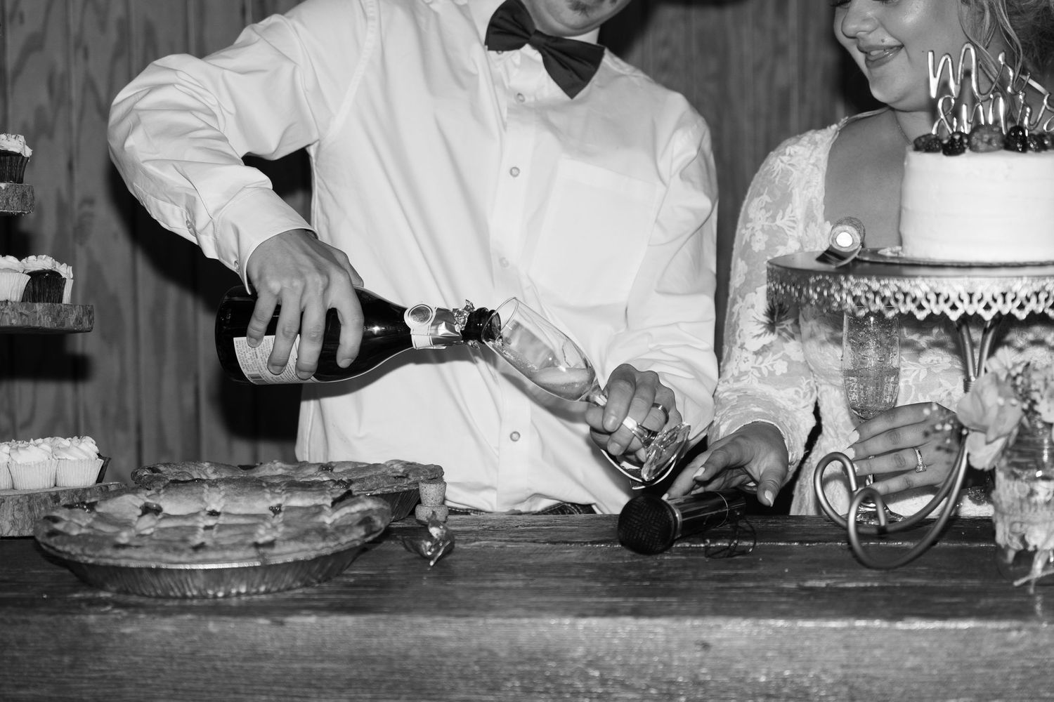 Wedding reception table with cake cutting and champagne pouring.