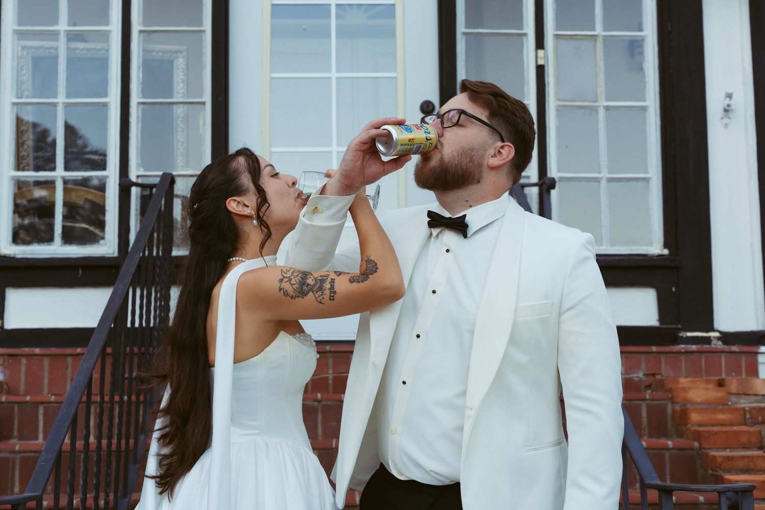 Wedding party in white attire poses in front of a classic white building.