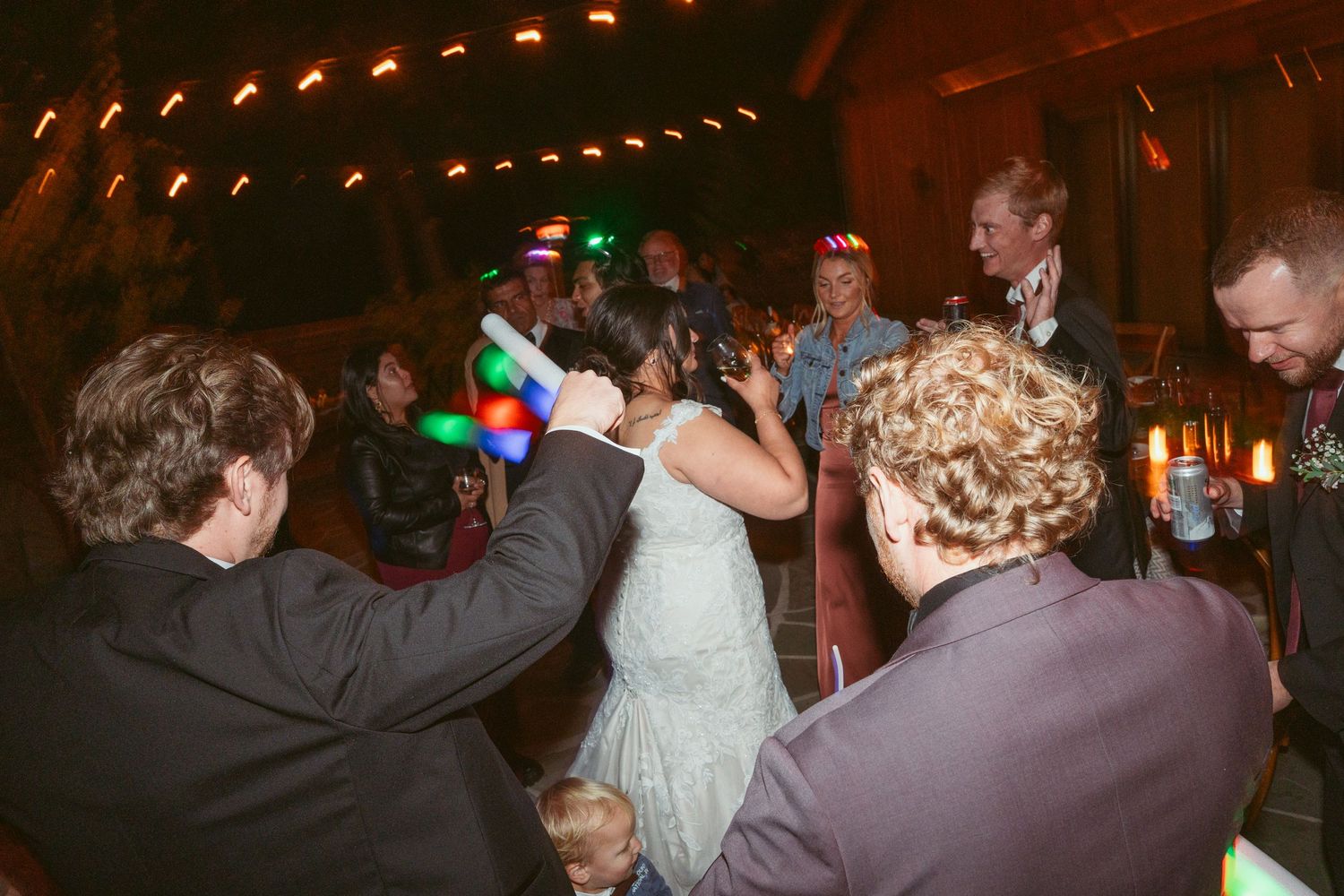 Wedding reception dance party with string lights creating warm ambiance.
