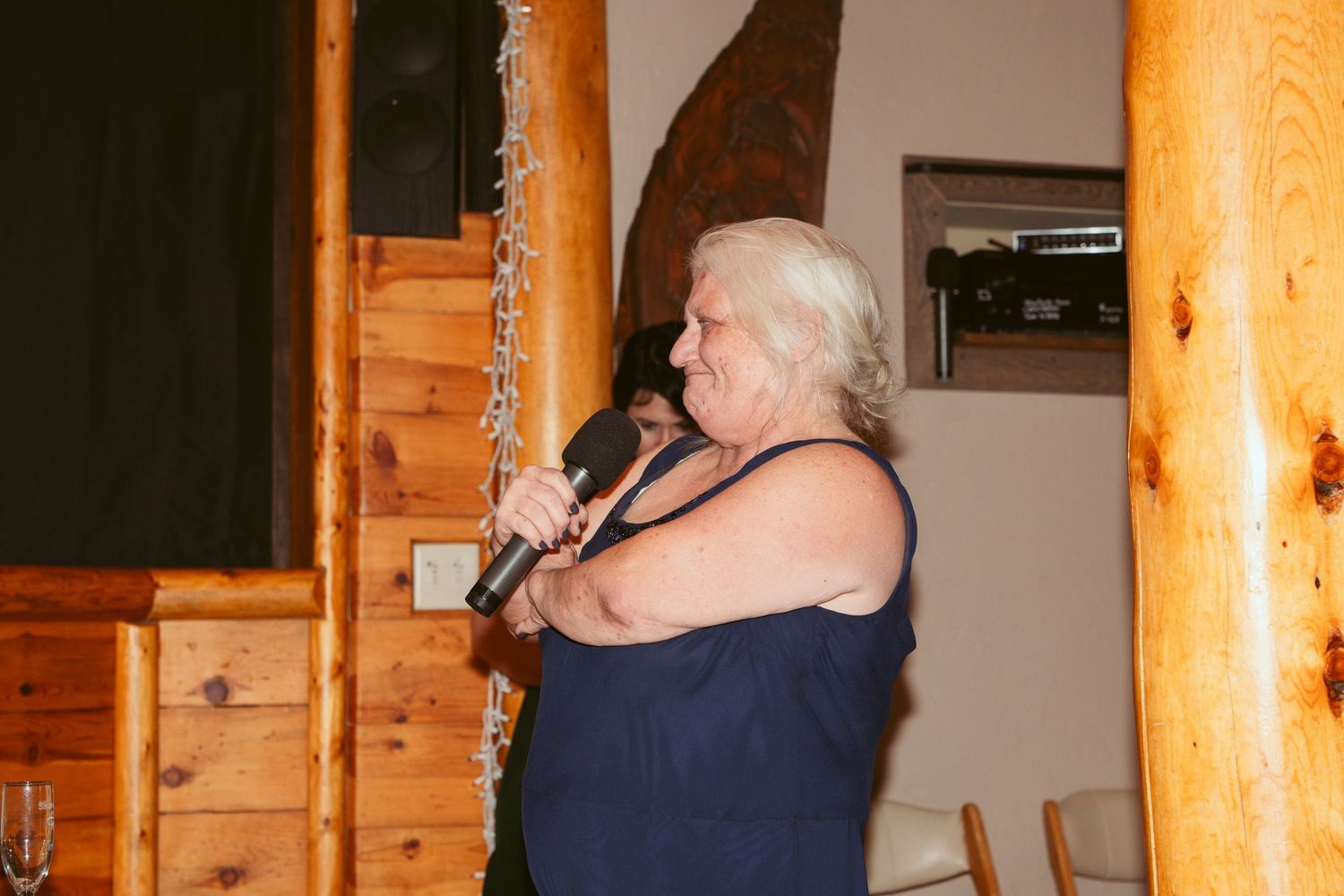 Indoor wedding reception space with wooden log pillars and warm lighting.