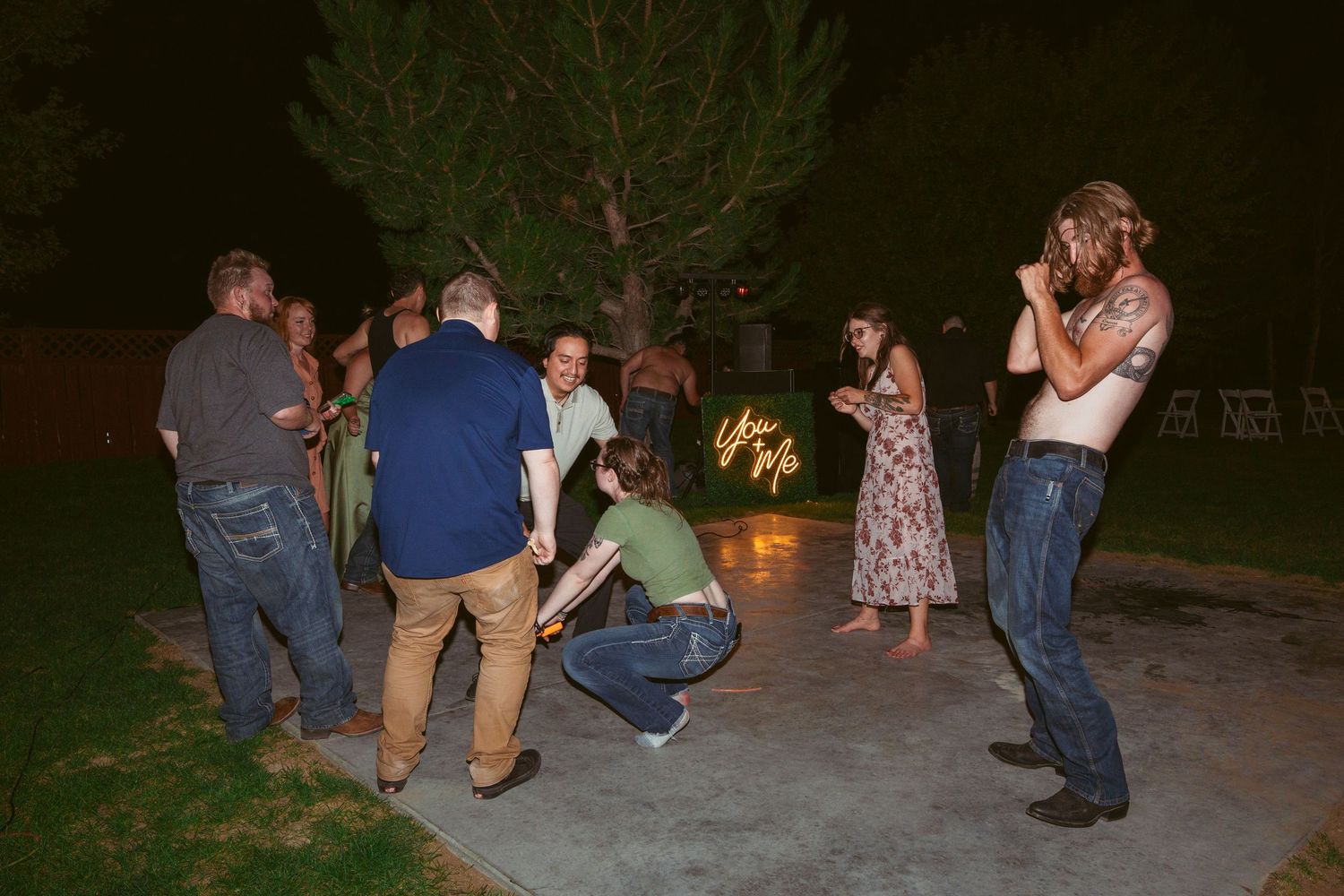 Wedding party members engage in playful poses during nighttime outdoor celebrations.