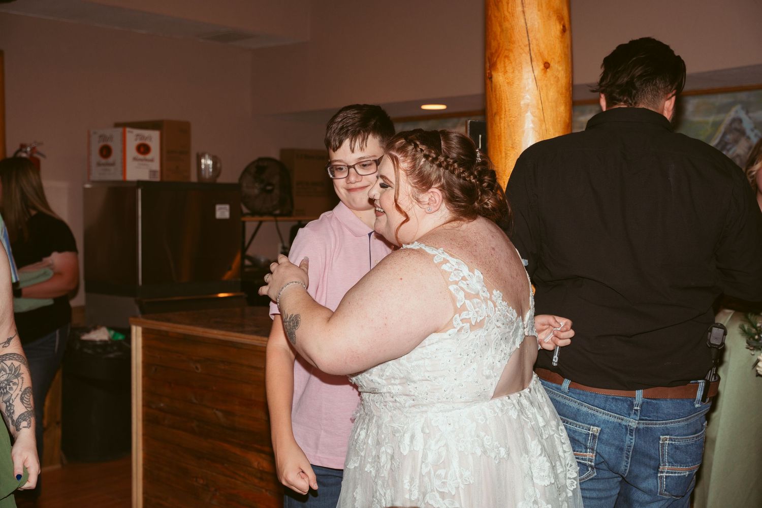 People dancing and embracing on a dimly lit dance floor at a celebration.