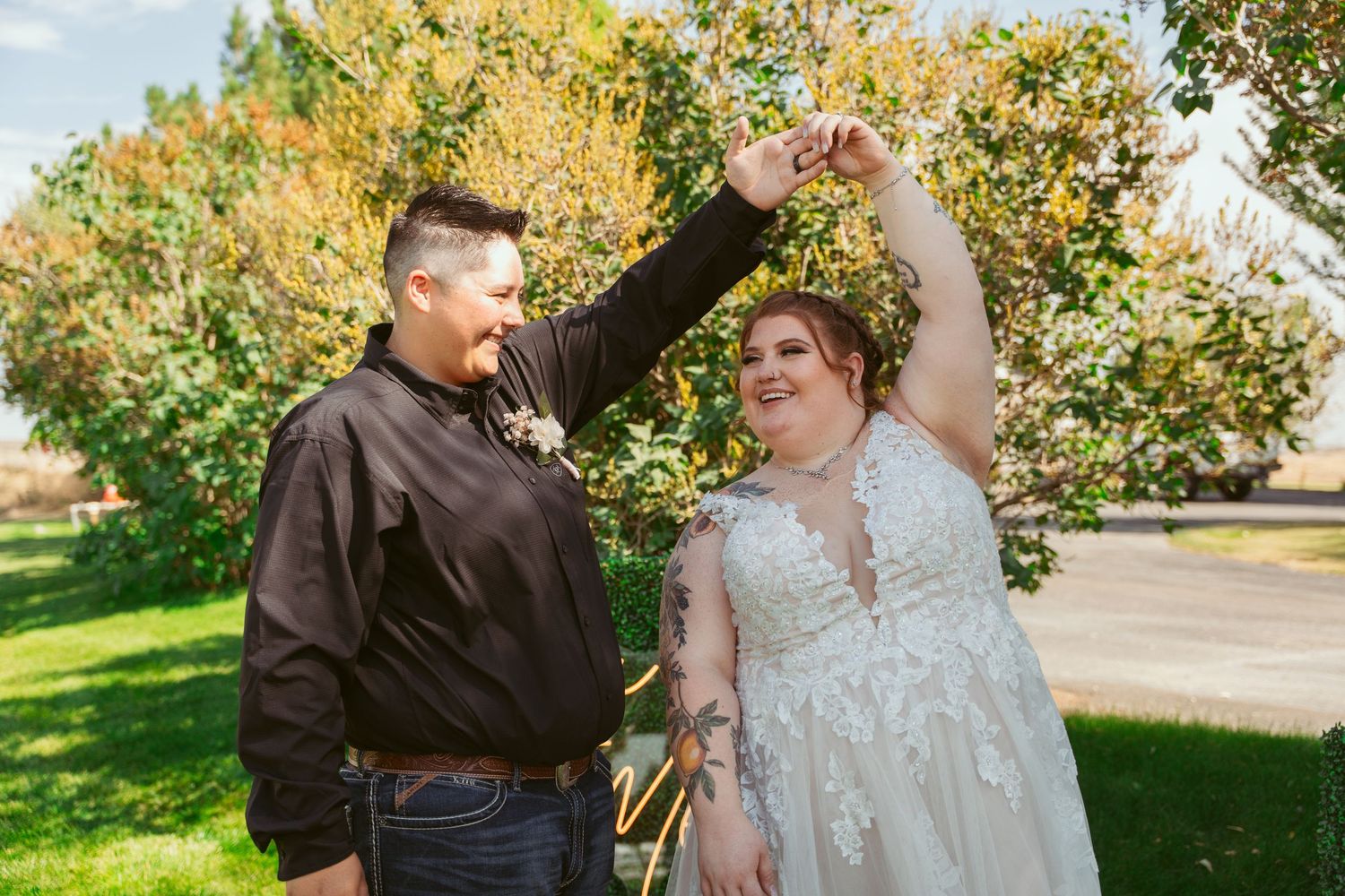 A couple shares a joyful dance moment together in a park with autumn trees in the background.